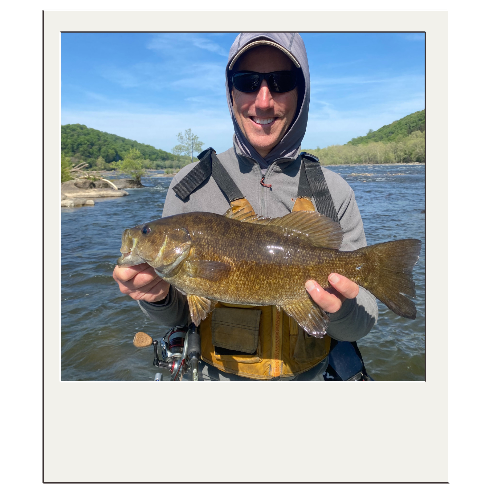 Smiling client holding a bass caught on a guided fly-fishing trip in the Harpers Ferry area.
