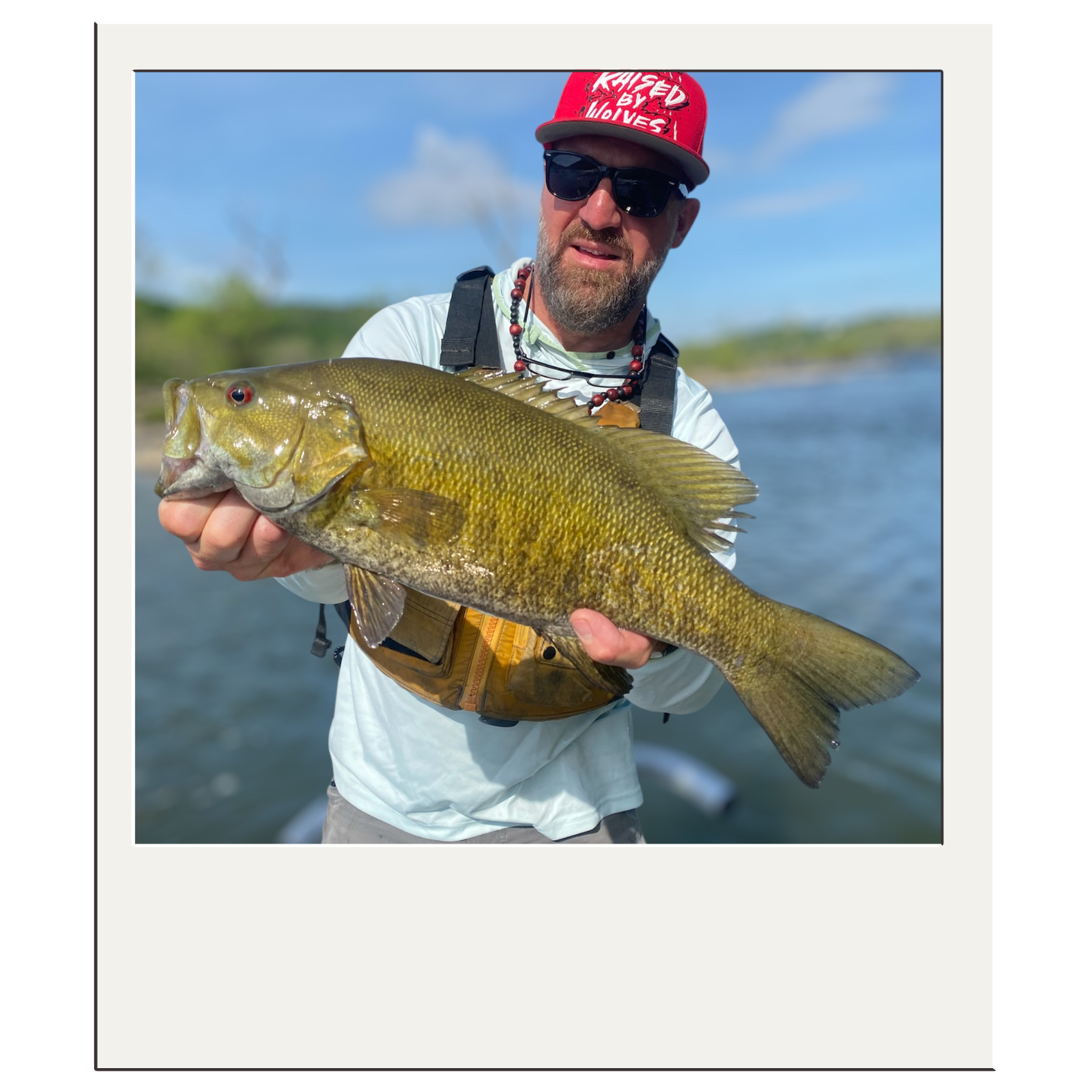 Smiling angler holding a smallmouth bass during a White Fly Outfitters guided adventure.