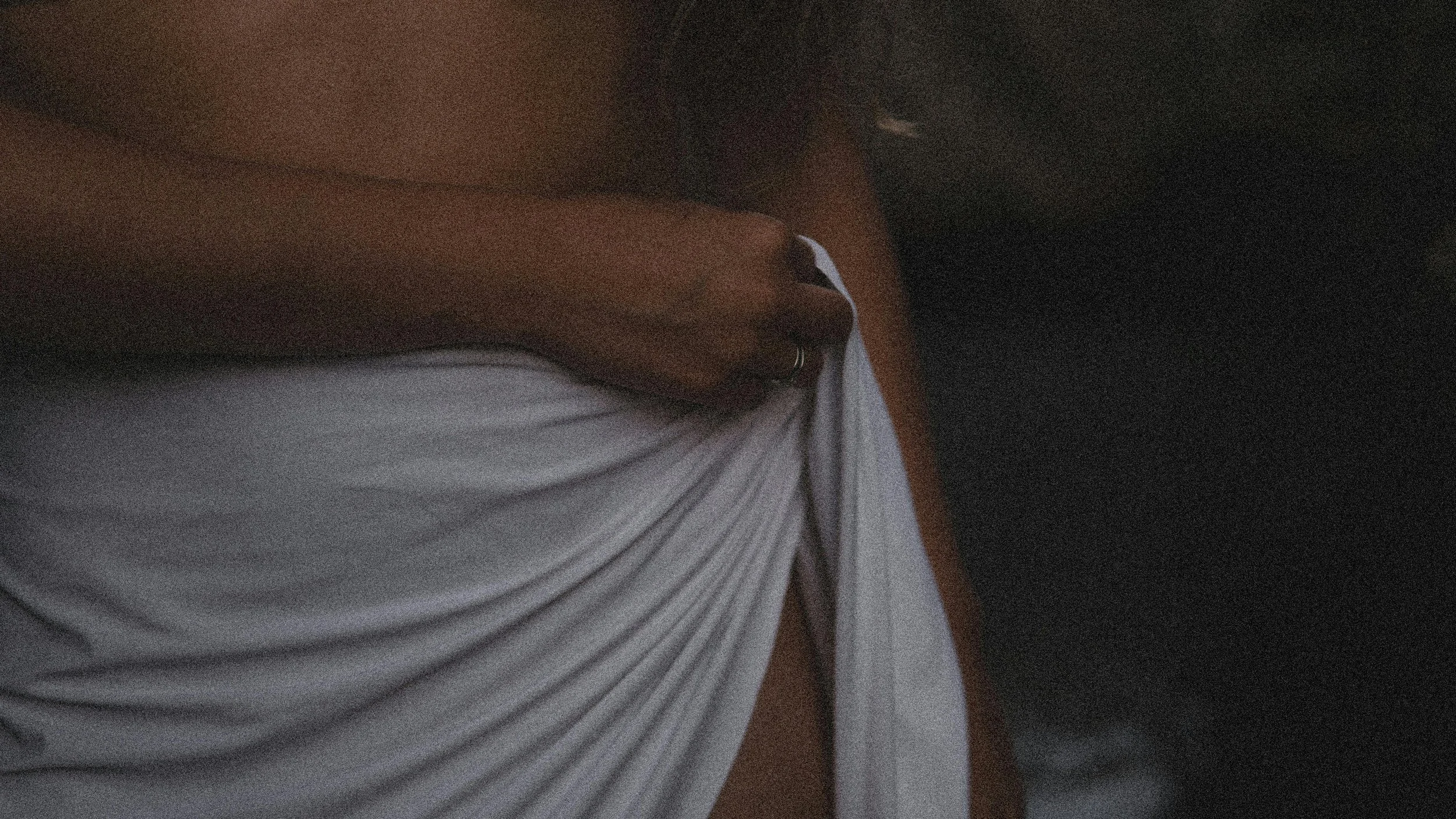 A person holding a spray bottle near their waist while wearing a white t-shirt and dark pants.