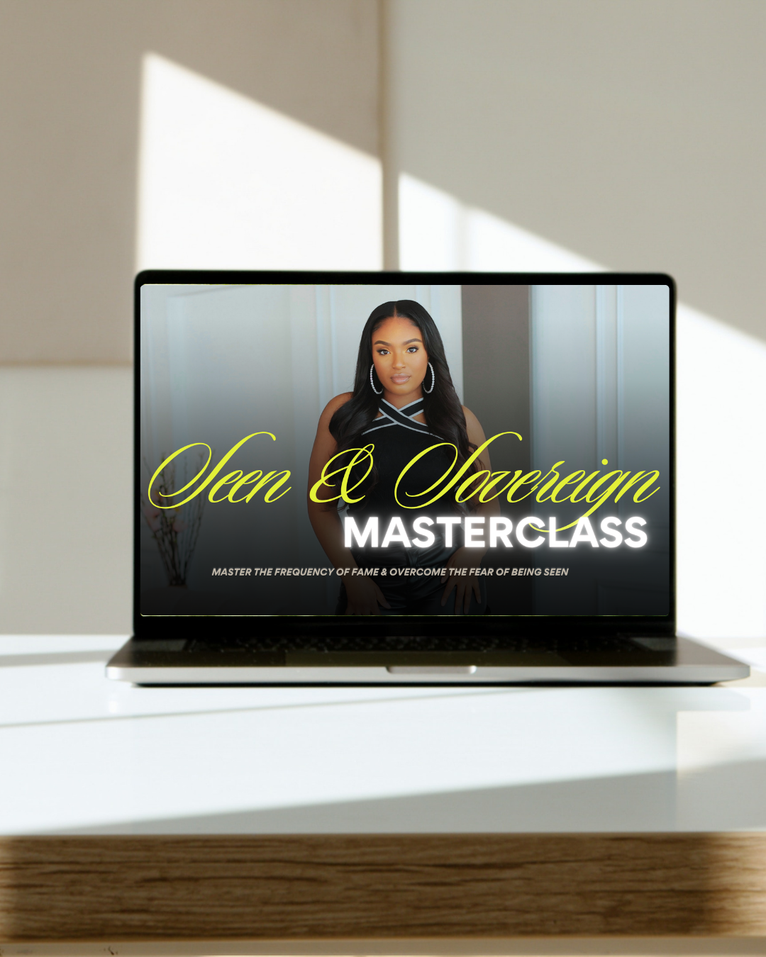 Laptop displaying a promotional graphic for 'Seer & Sovereign Masterclass' with a woman in a black dress with long black hair, hoop earrings, and a serious expression, standing in front of a gray door.