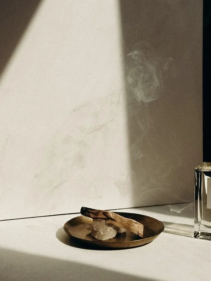 A small wooden dish with a stick and a rock, with some smoke rising in the background.