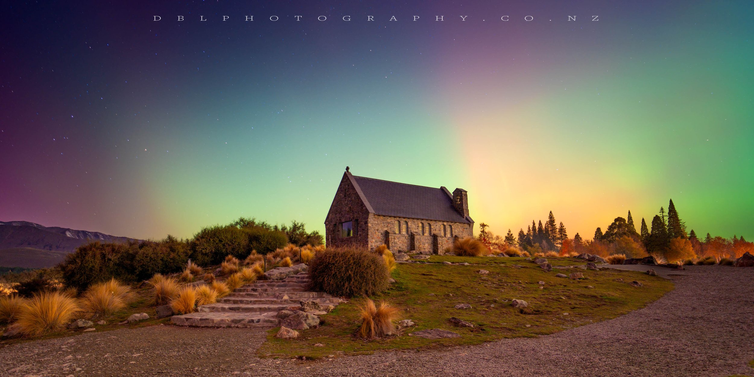 A small stone church at night with the northern lights in the sky and stars visible.