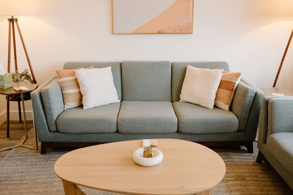 Family therapy room with a sofa and oak coffee table at Forbes Individual and Family Therapy in Newport Beach
