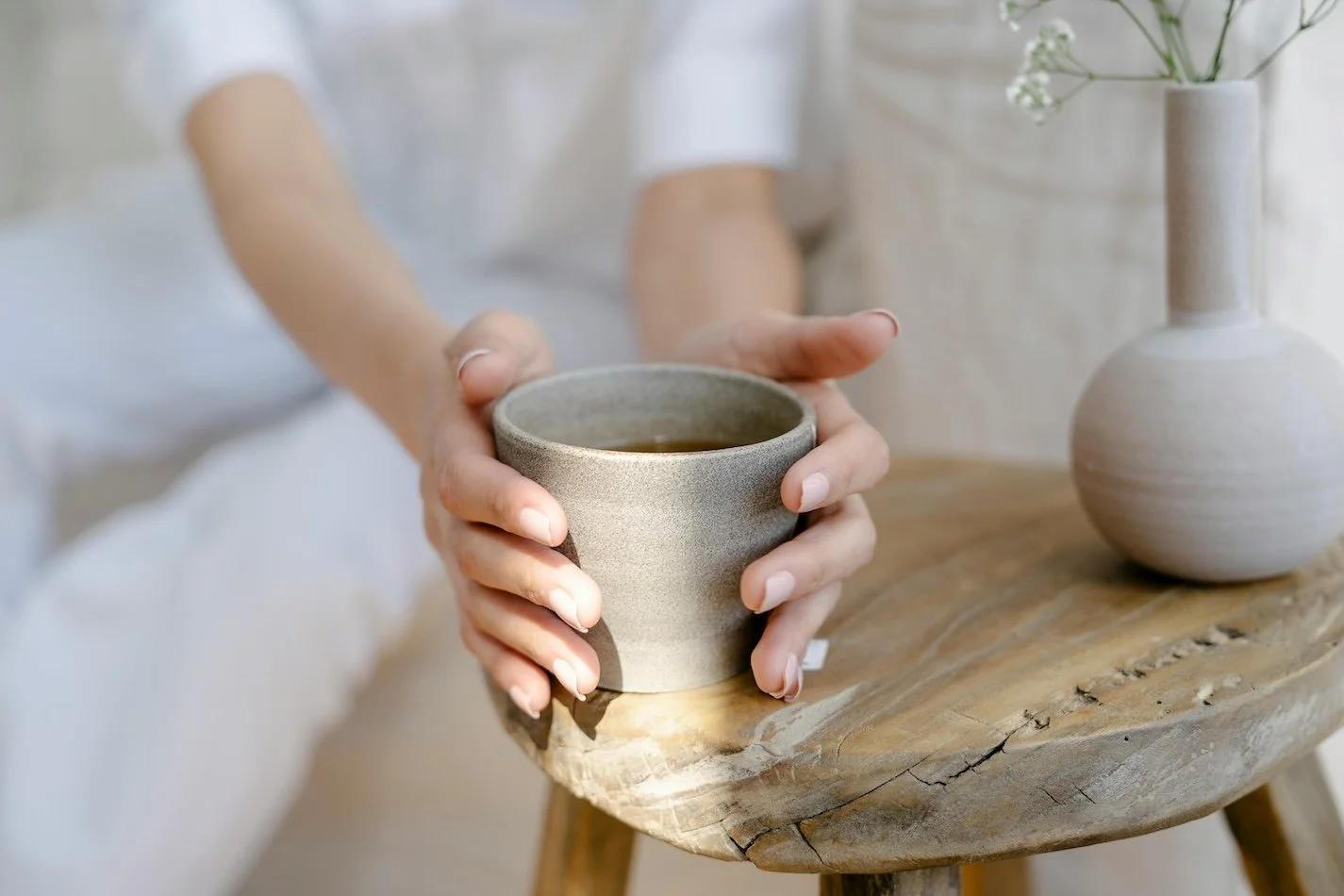 Hand holding ceramic tea cup on rustic table with flowers | herbal tea wellness and holistic health photo