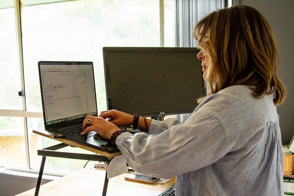 Woman, Kate Holman, Naturopath working on laptop by window | holistic business and wellness workspace imagery for Simple Holistic Health