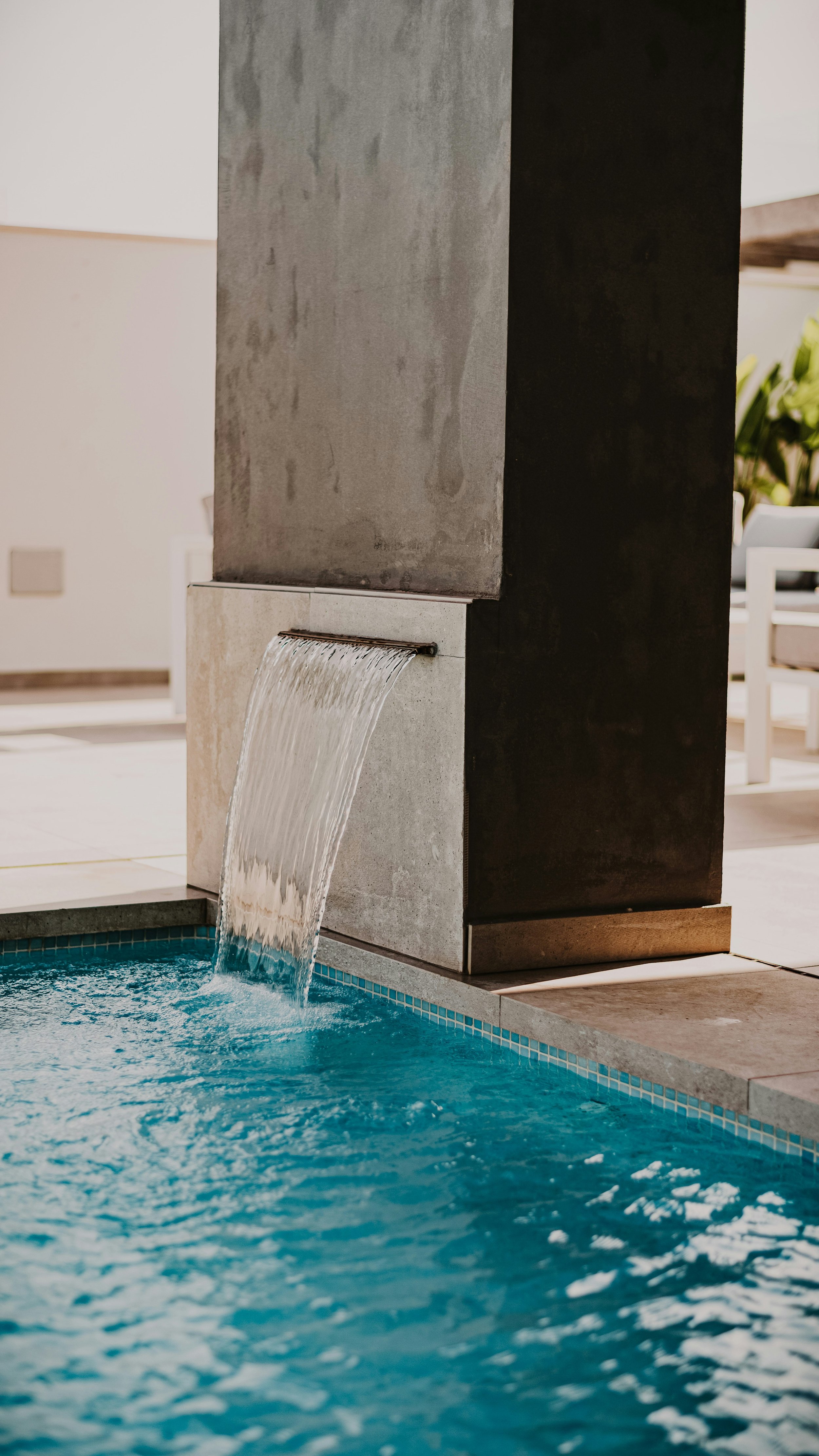 Water flowing from a fountain into a swimming pool in an indoor setting.