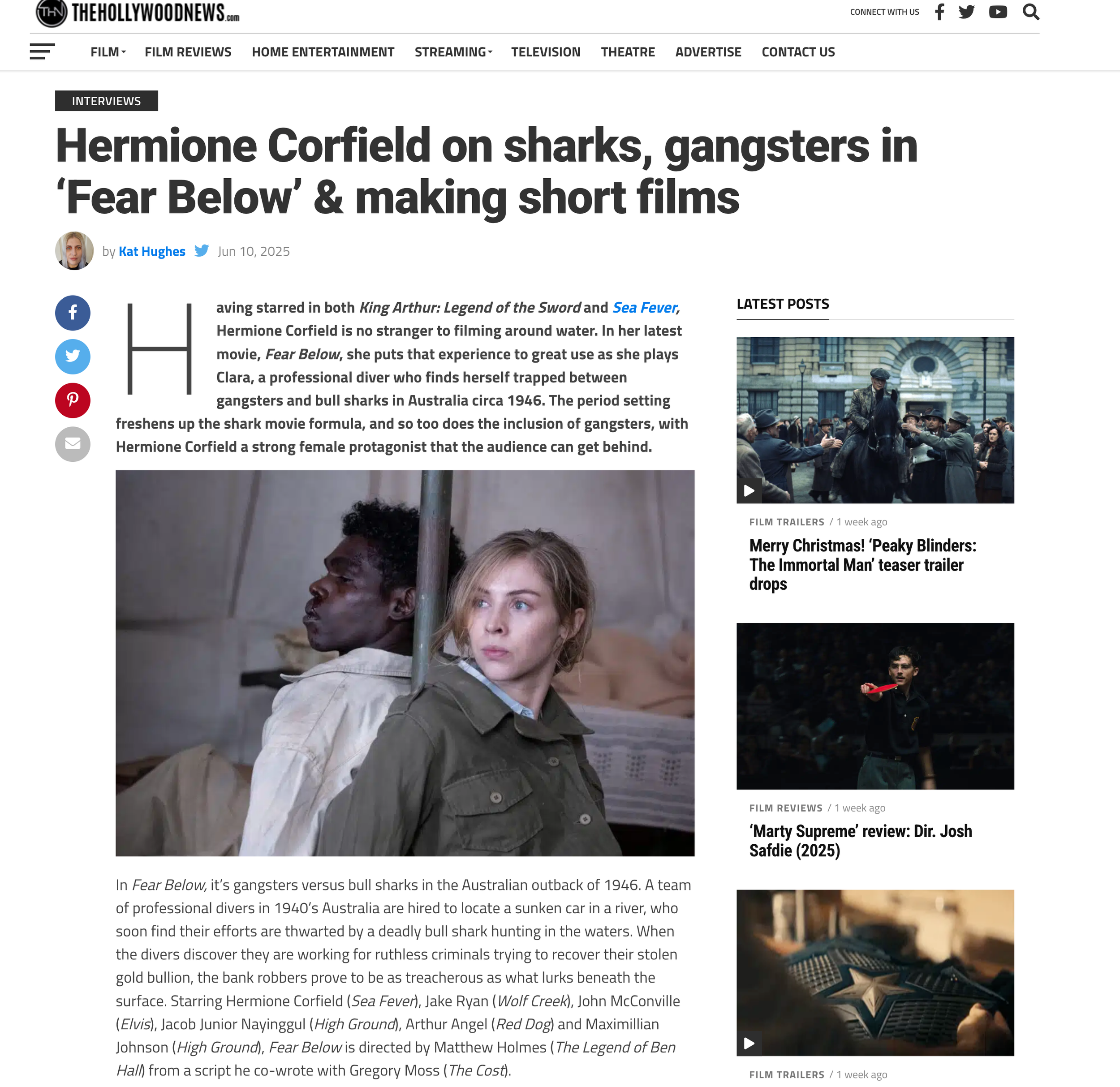 A close-up photograph of two young actors, a male and a female, on a film set. The female has blonde hair, blue eyes, and is wearing a green jacket. She appears to be looking off to the side with a thoughtful expression, while the male has dark curly