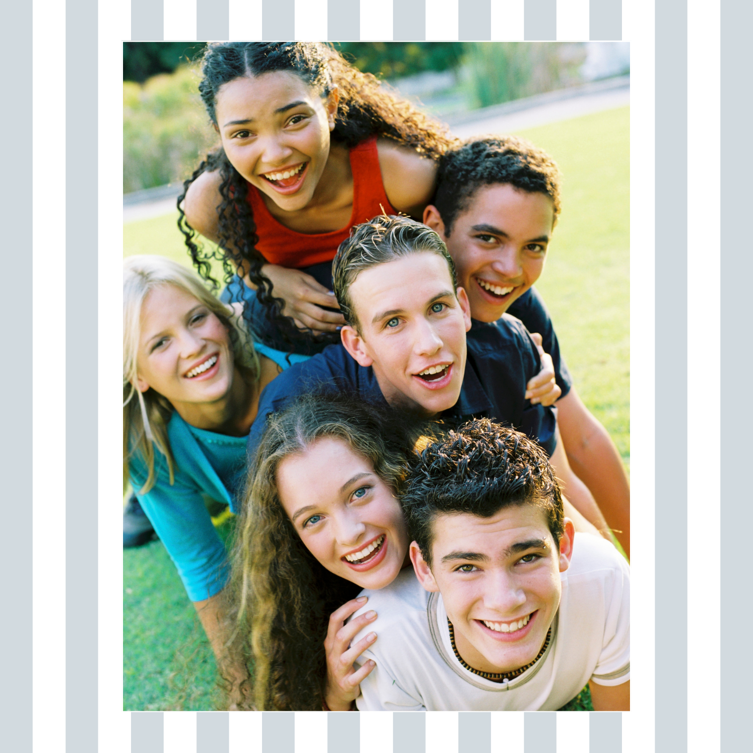 Diverse group of smiling teens gathered closely together outdoors, representing connection, friendship, and peer support in teen group therapy.