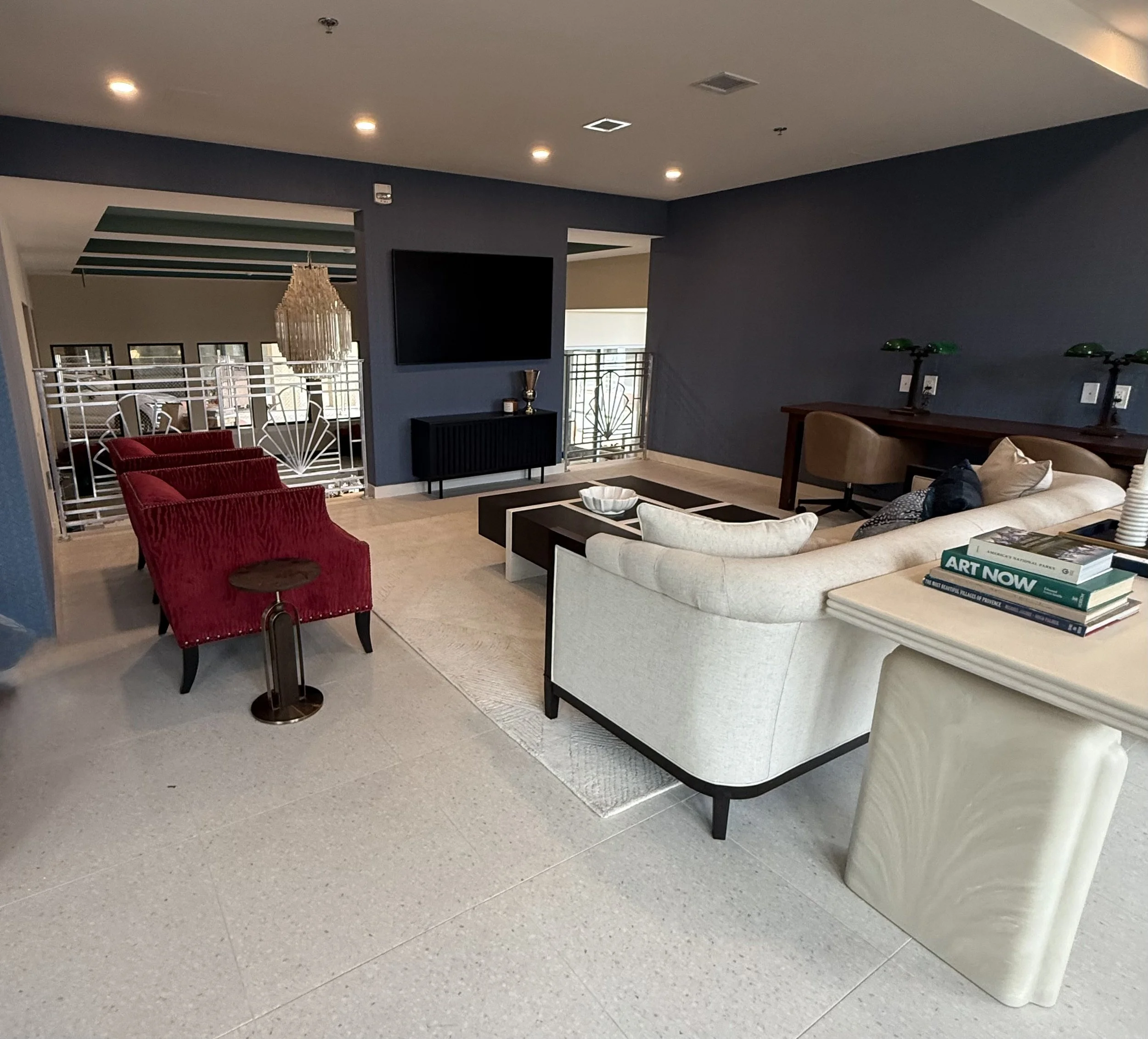 Living room with white sofa, red armchairs, black TV, and various decorative items.