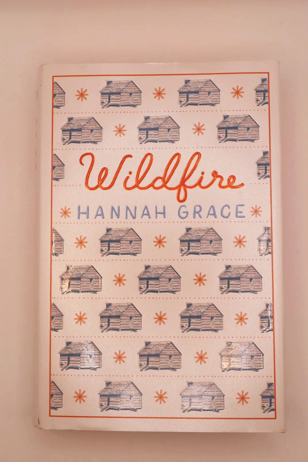 Front cover of Wildfire by Hannah Grace, decorated with a repeating pattern of small blue cabins.