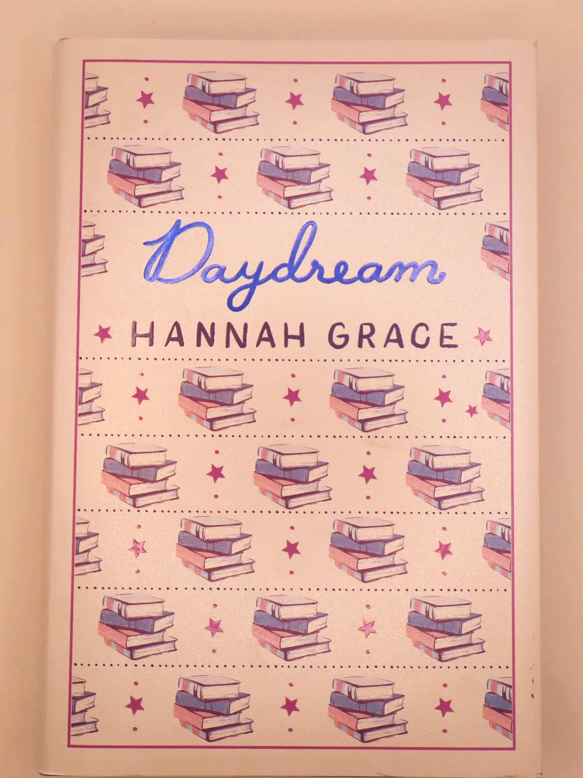 Front cover of Daydream by Hannah Grace, featuring a repeating pattern of stacked books and stars.