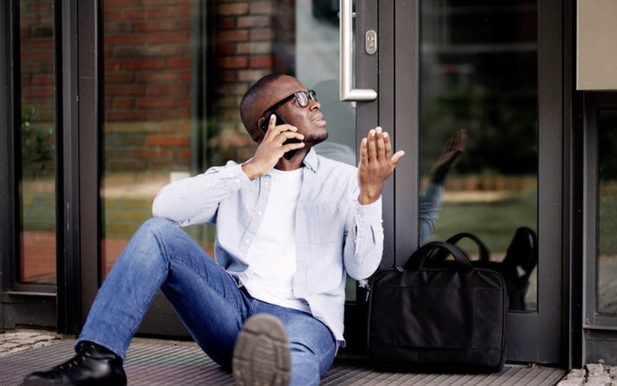 african american male sitting outside a commerical building locked out.