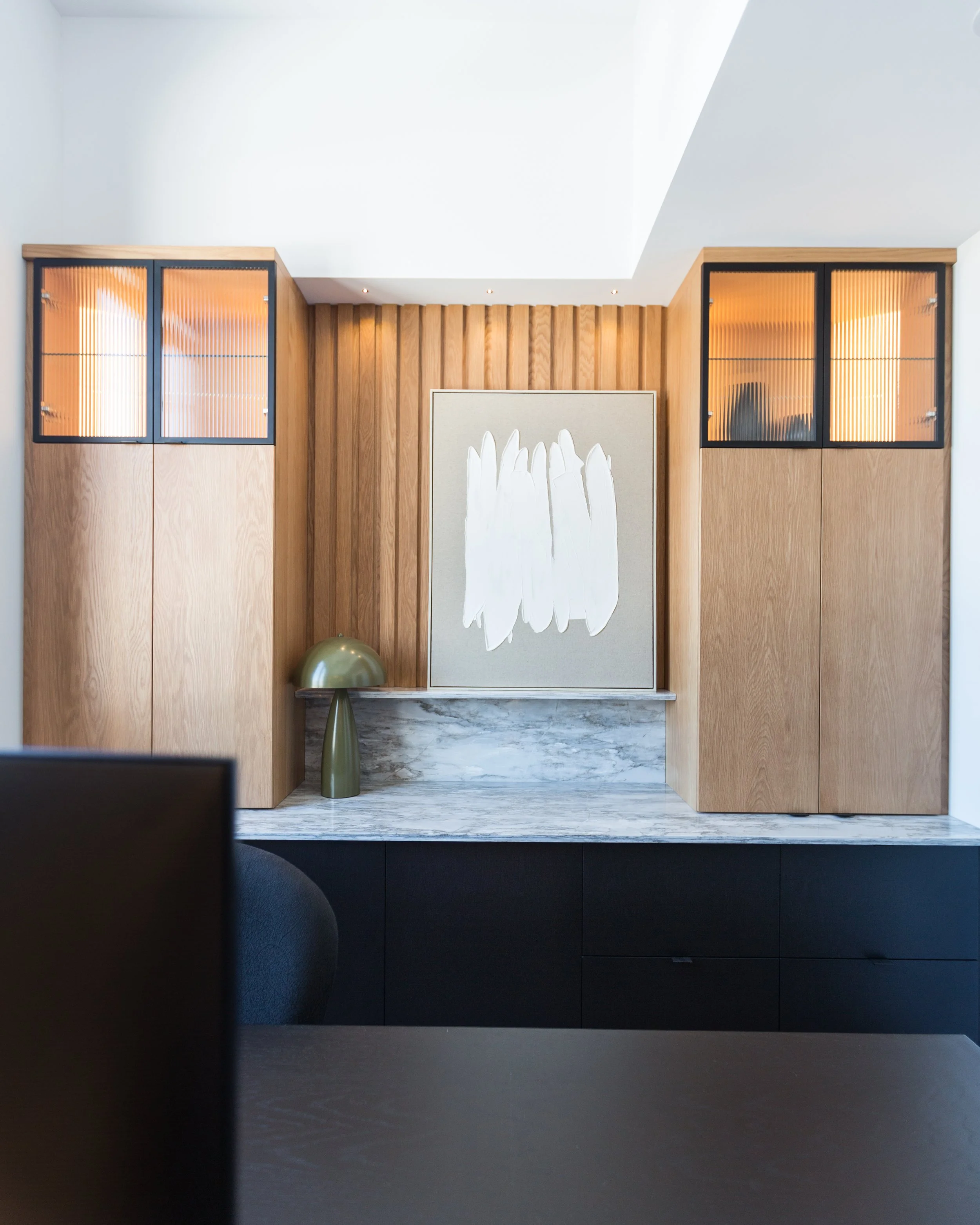 Modern interior with wooden cabinets, abstract artwork, and marble surface
