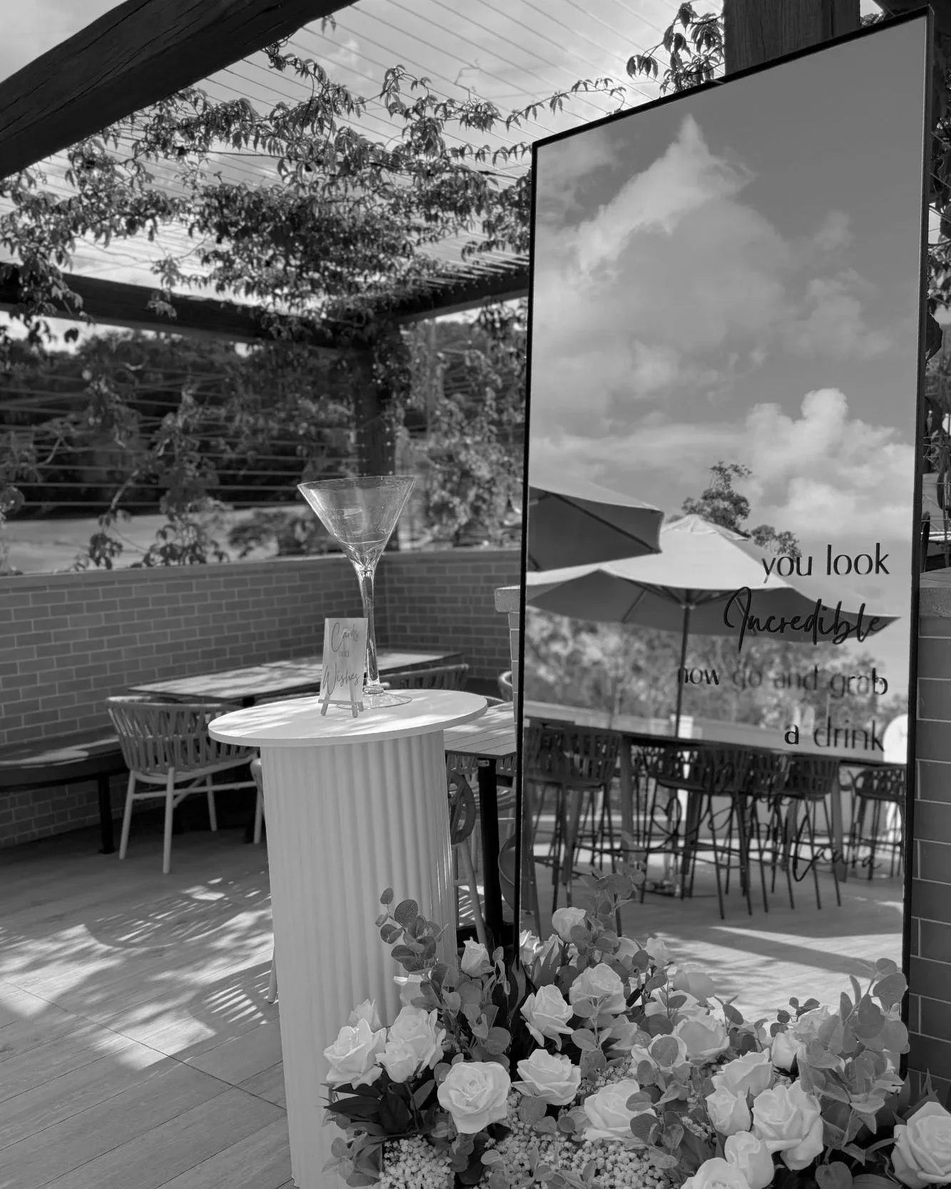 Outdoor event styling with personalised mirror signage, white plinth cocktail table and florals at Tallai Golf Club by Saudade Events.
