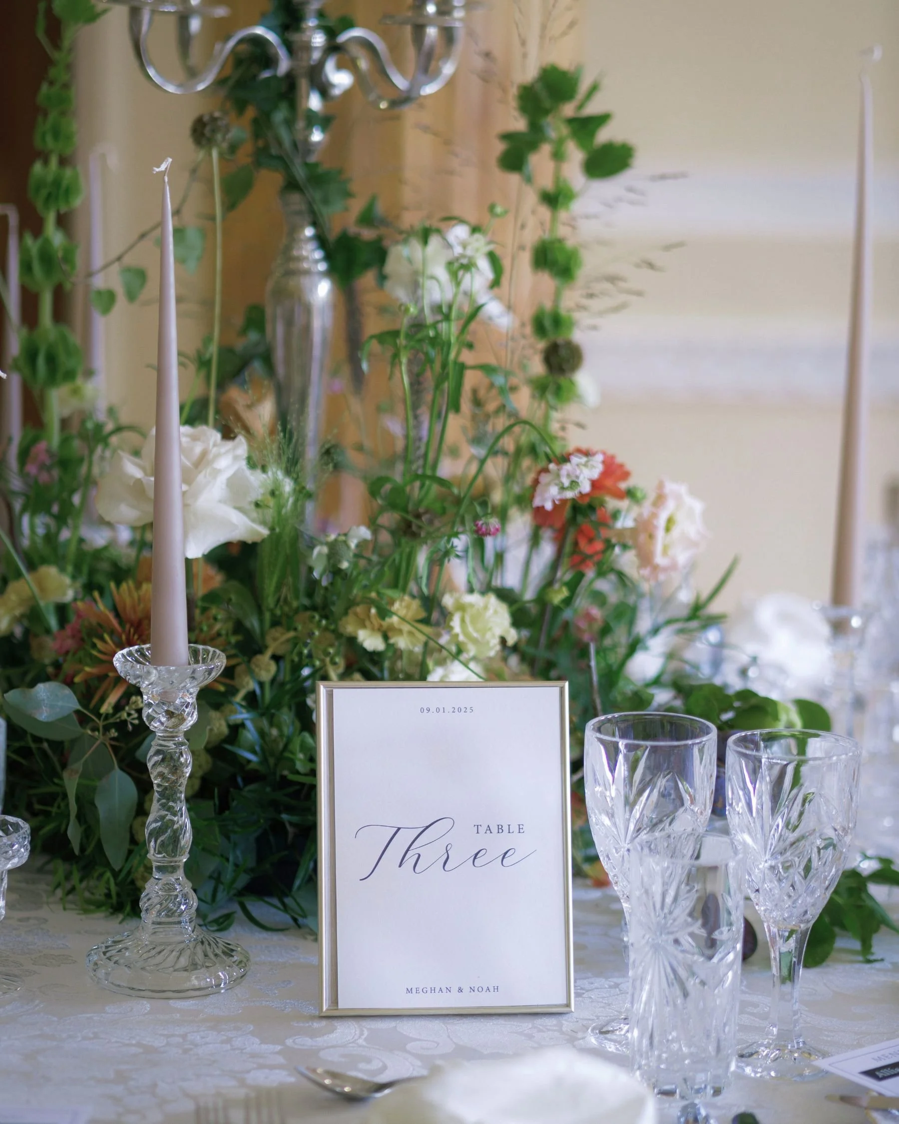 Wedding reception table styling in Gold Coast with custom table number stationery, floral centrepiece and refined glassware by Saudade Events.