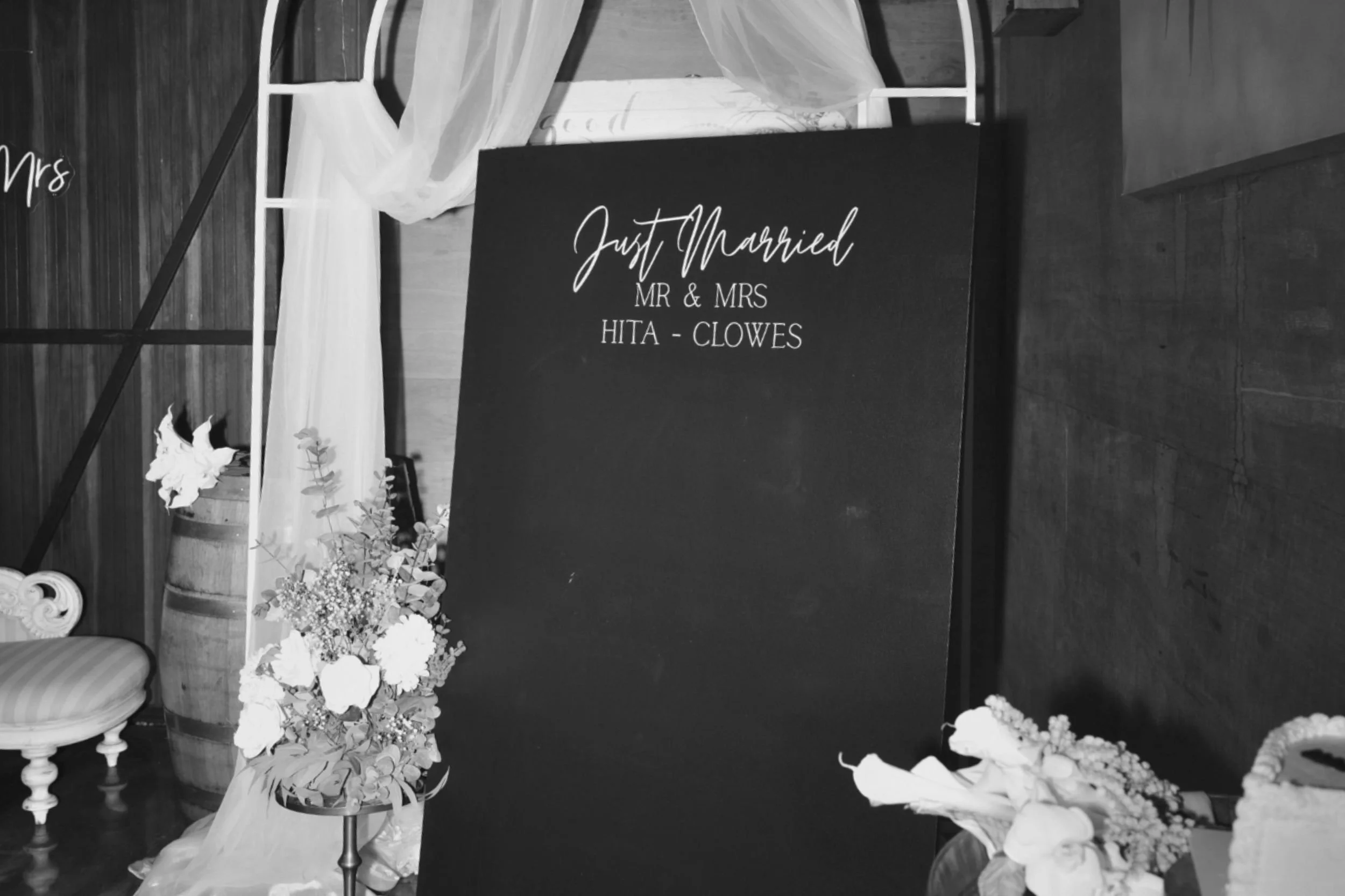Elegant wedding event styling setup featuring custom black signage, draped fabric and florals, designed by Saudade Events on the Gold Coast.