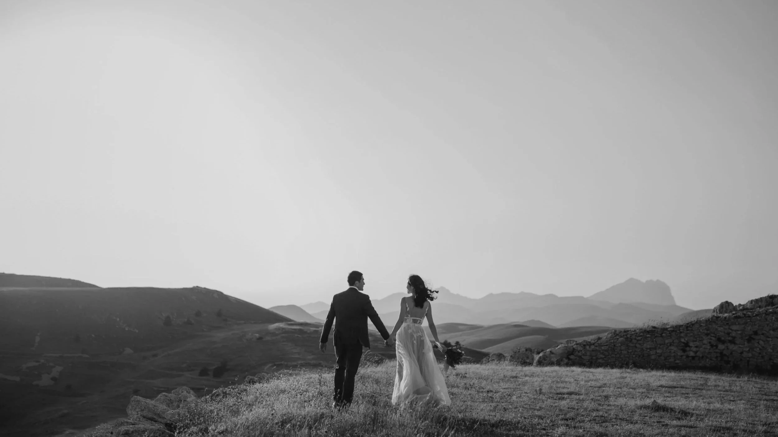 Bride and groom walking hand in hand across a scenic landscape, reflecting refined wedding and event styling by Saudade Events on the Gold Coast.