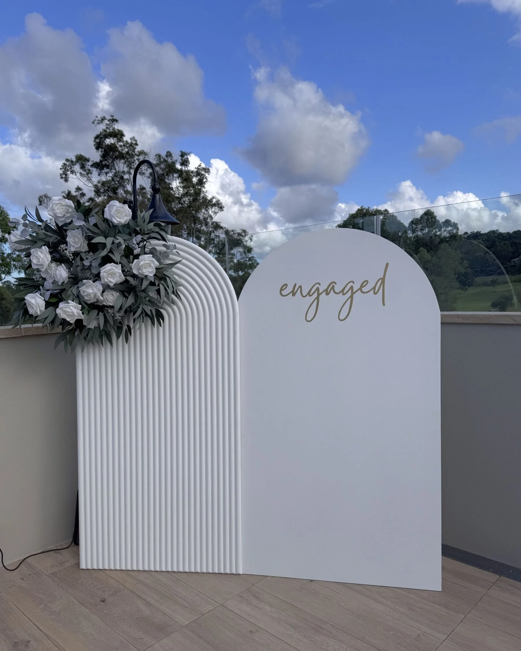 Engagement party backdrop setup at Tallai Golf Club in Gold Coast with custom arched panels and floral styling by Saudade Events.