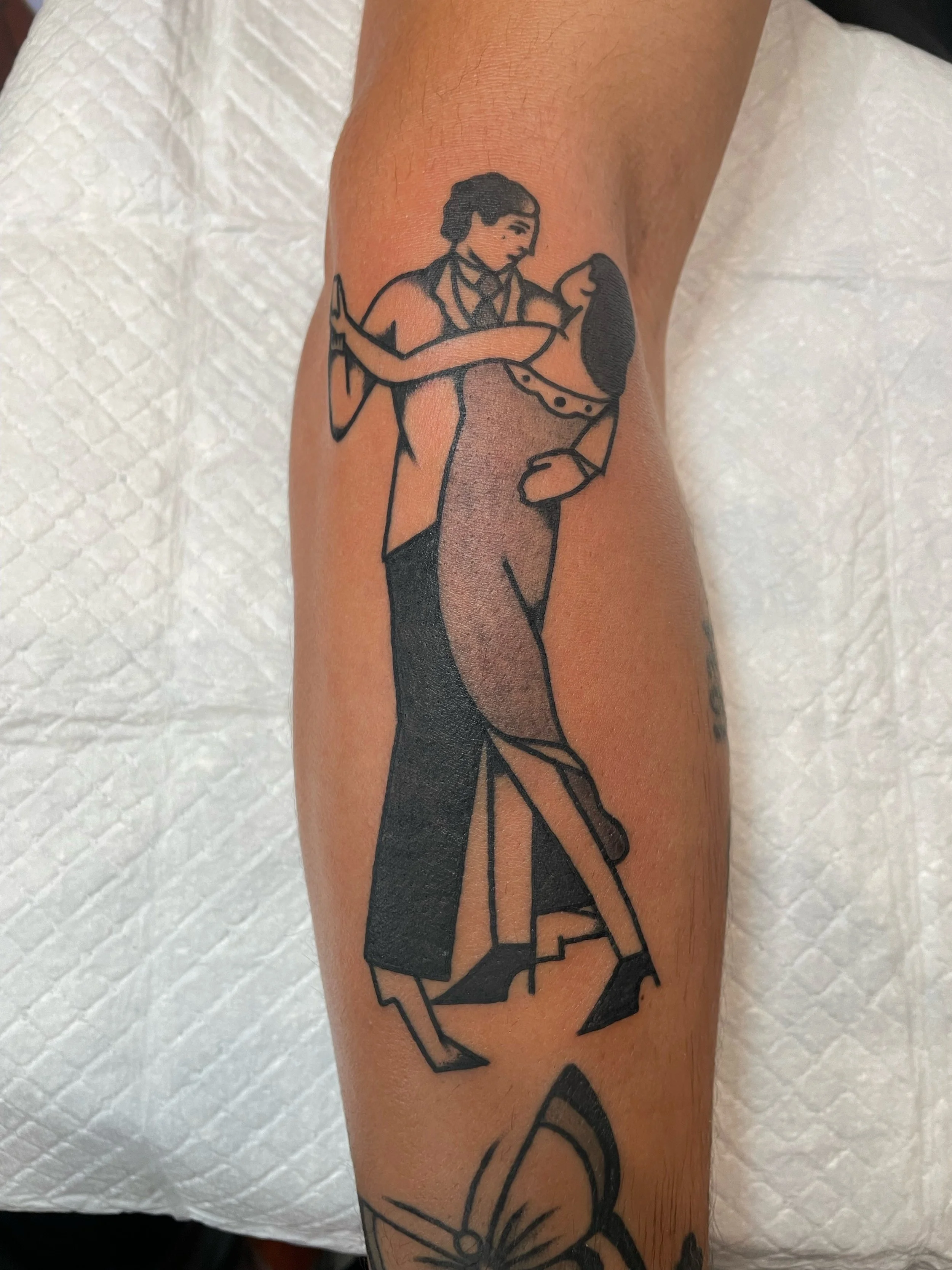Tattoo of a person dancing with a woman, holding her in an embrace.
