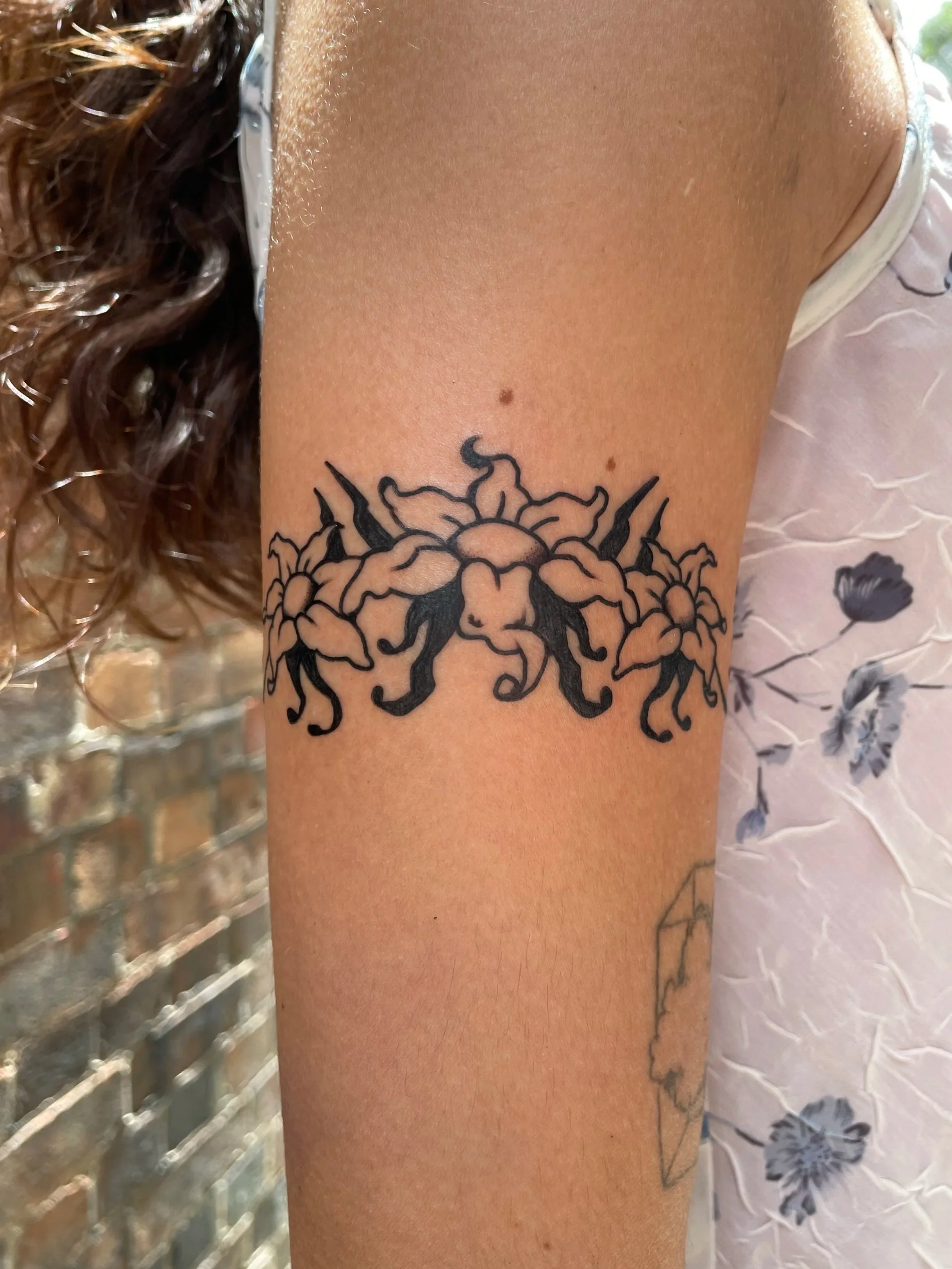 A tattoo of flowers and flowing hair on a person's upper arm.