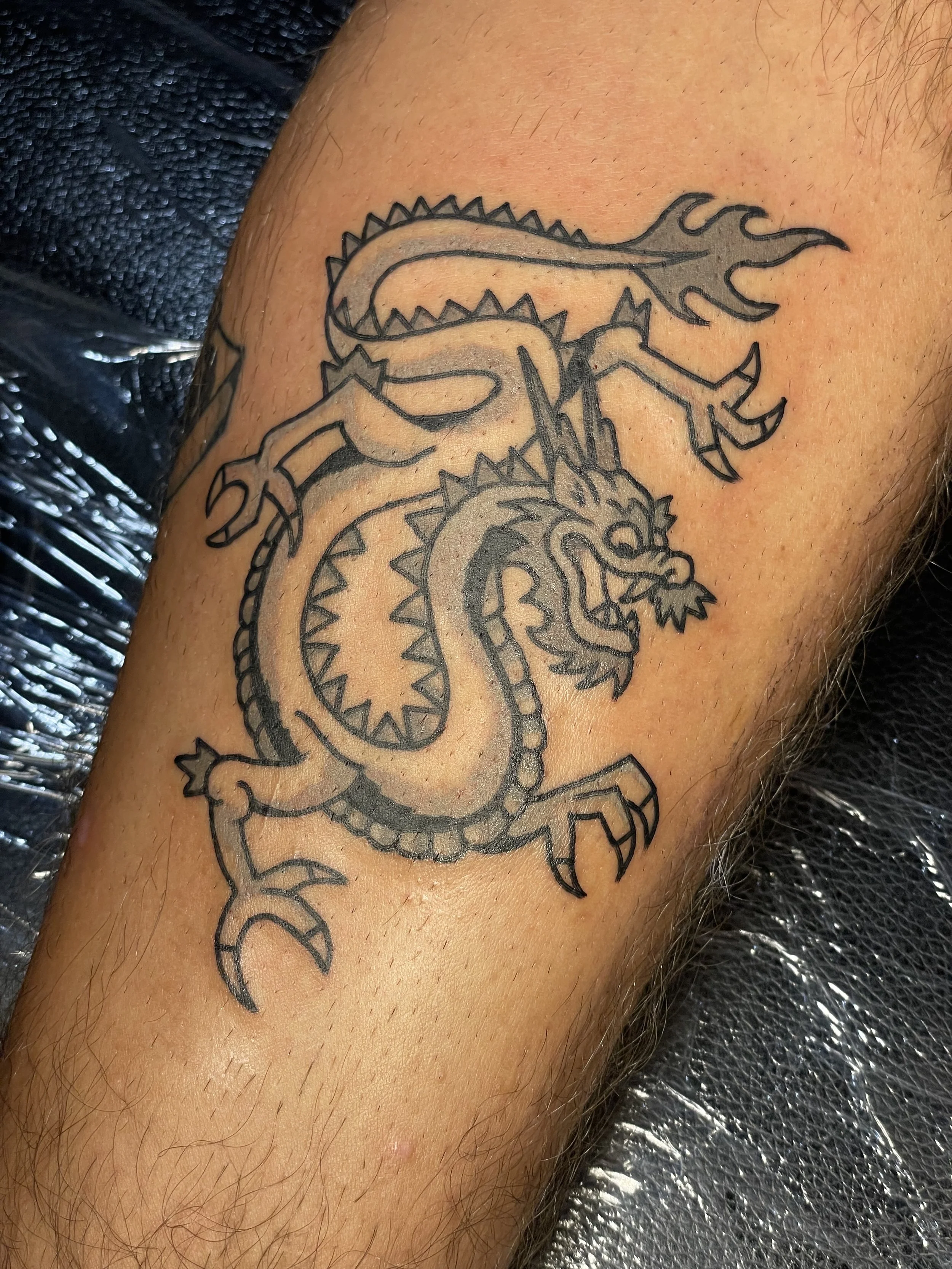 Tattoo of a traditional dragon on a person's arm.