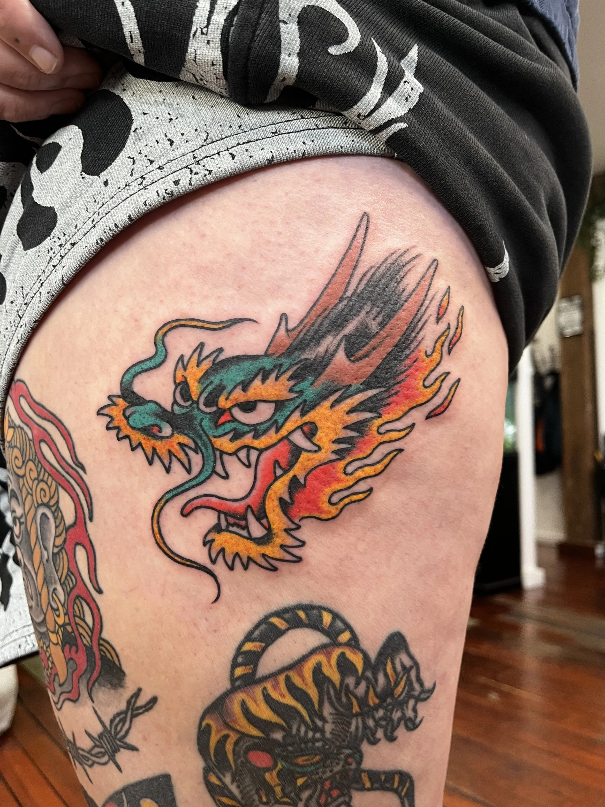Tattoo of a colorful Chinese dragon on upper thigh.