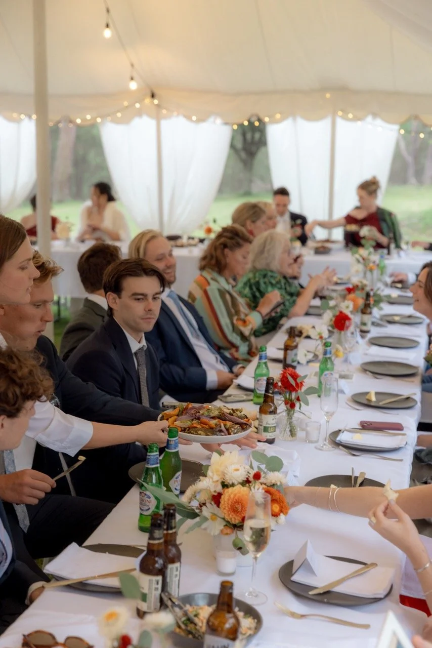 Wedding guests seated at a long outdoor table sharing a farm-style dinner under the marquee at Kingaley, Hunter Valley