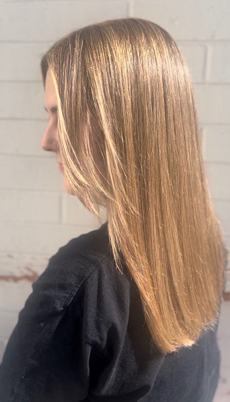 Side view of a woman with straight, shiny, light brown hair.