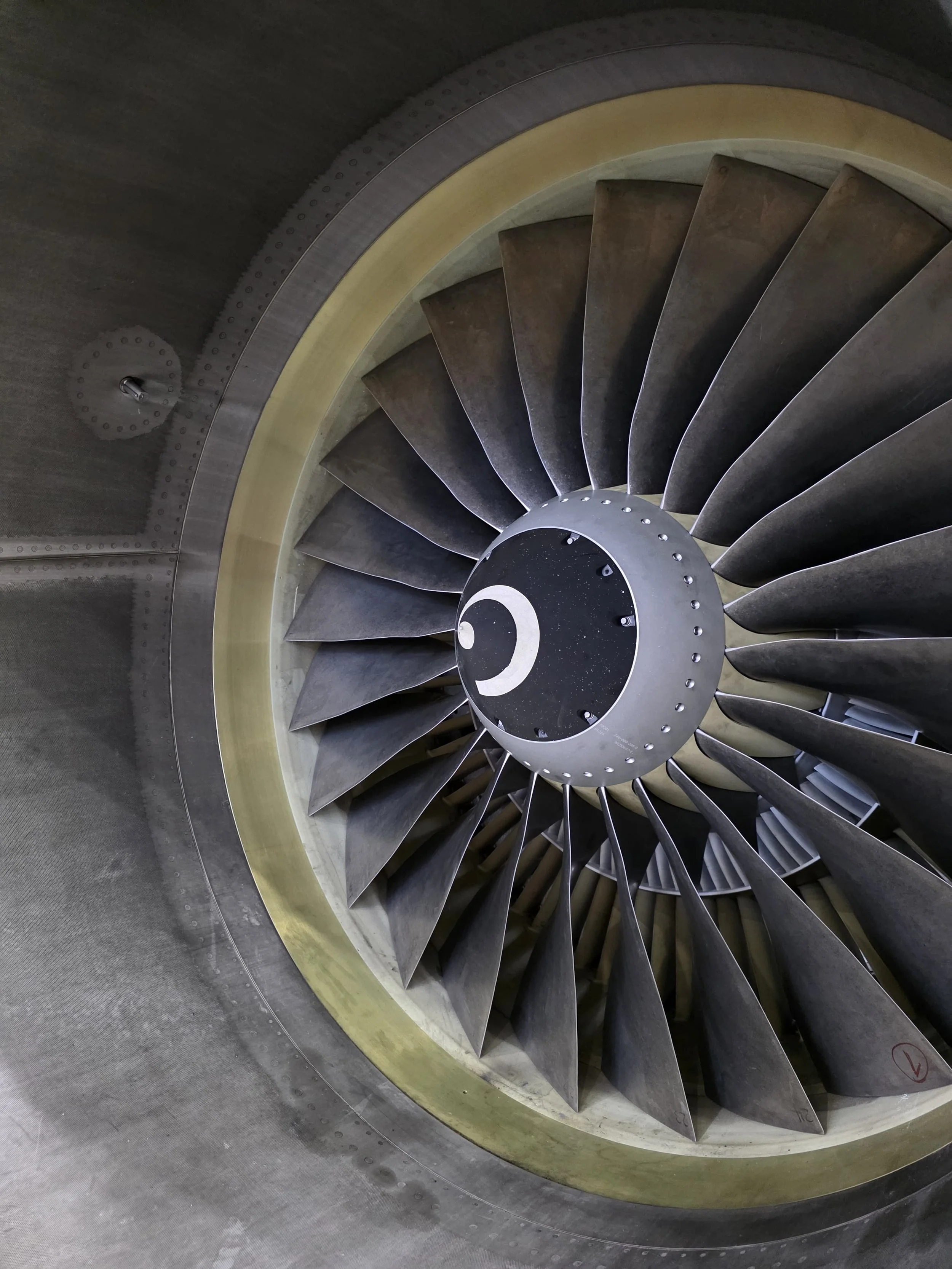 Close-up view of a jet engine's turbine blades and central hub with a black circle featuring a white crescent moon design.