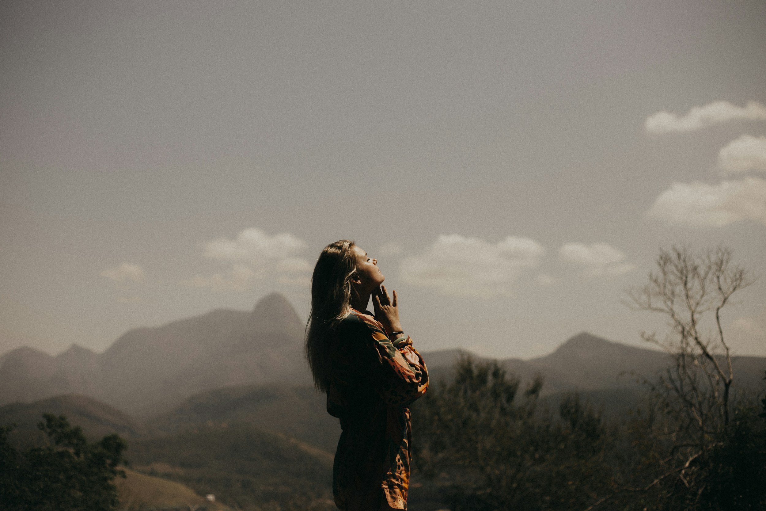 Woman gazing up at mountains and sky, reflecting the expansive, introspective nature of psychedelic-assisted therapy