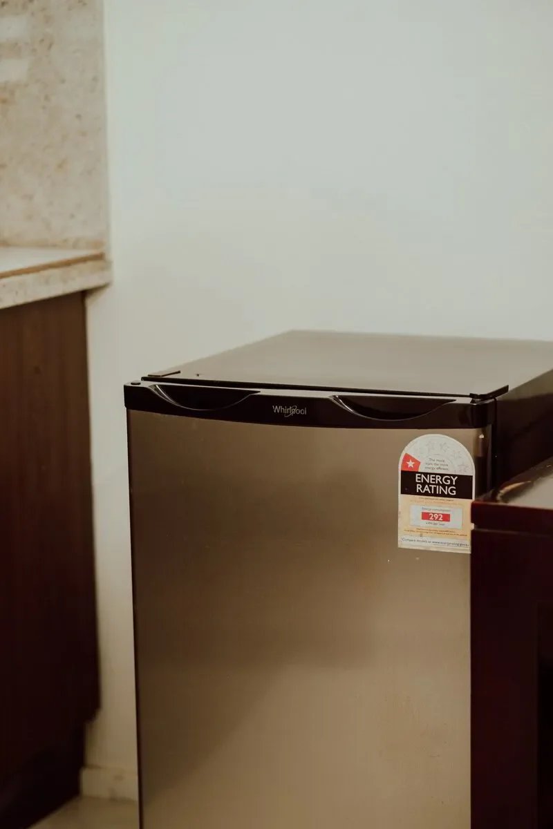Stainless steel Whirlpool mini refrigerator in a kitchen corner.