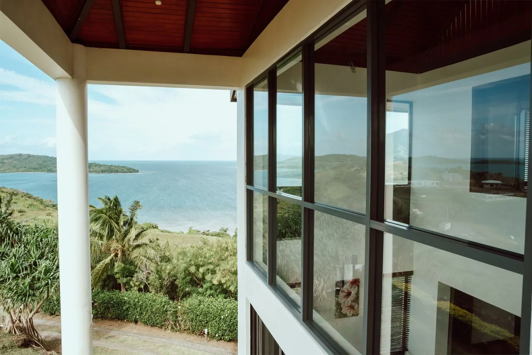 View from a balcony overlooking a body of water with small islands or landmasses and a partly cloudy sky.
