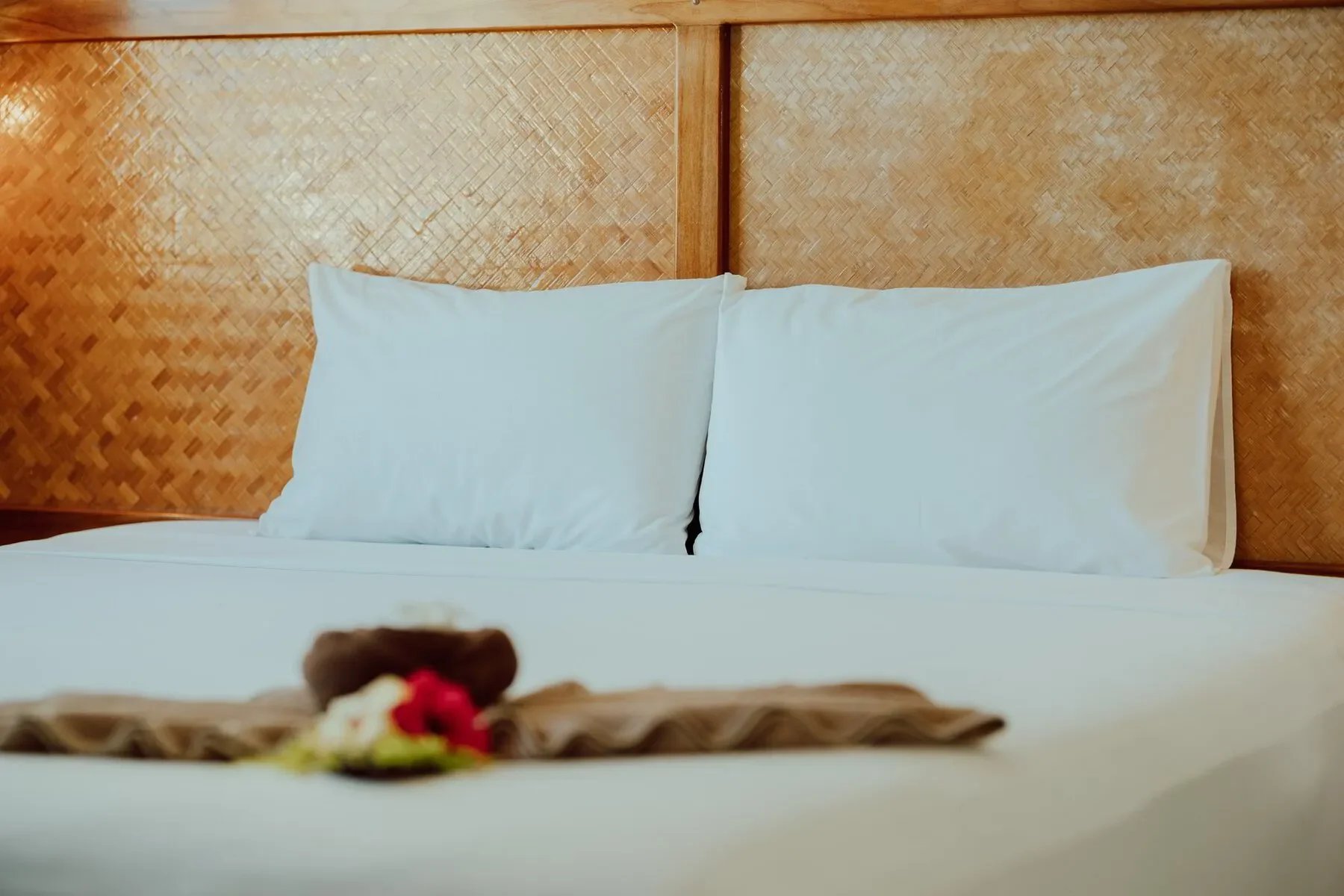 Hospital bed with white pillows and a headboard made of woven wood.