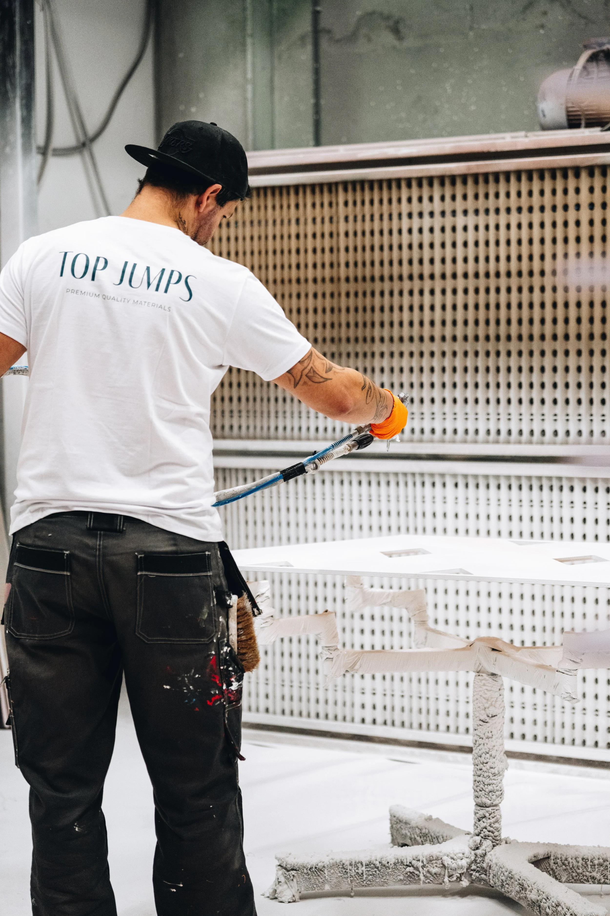 Professional behind the scenes photo of a craftsman spray-painting jump elements for Top Jumps
