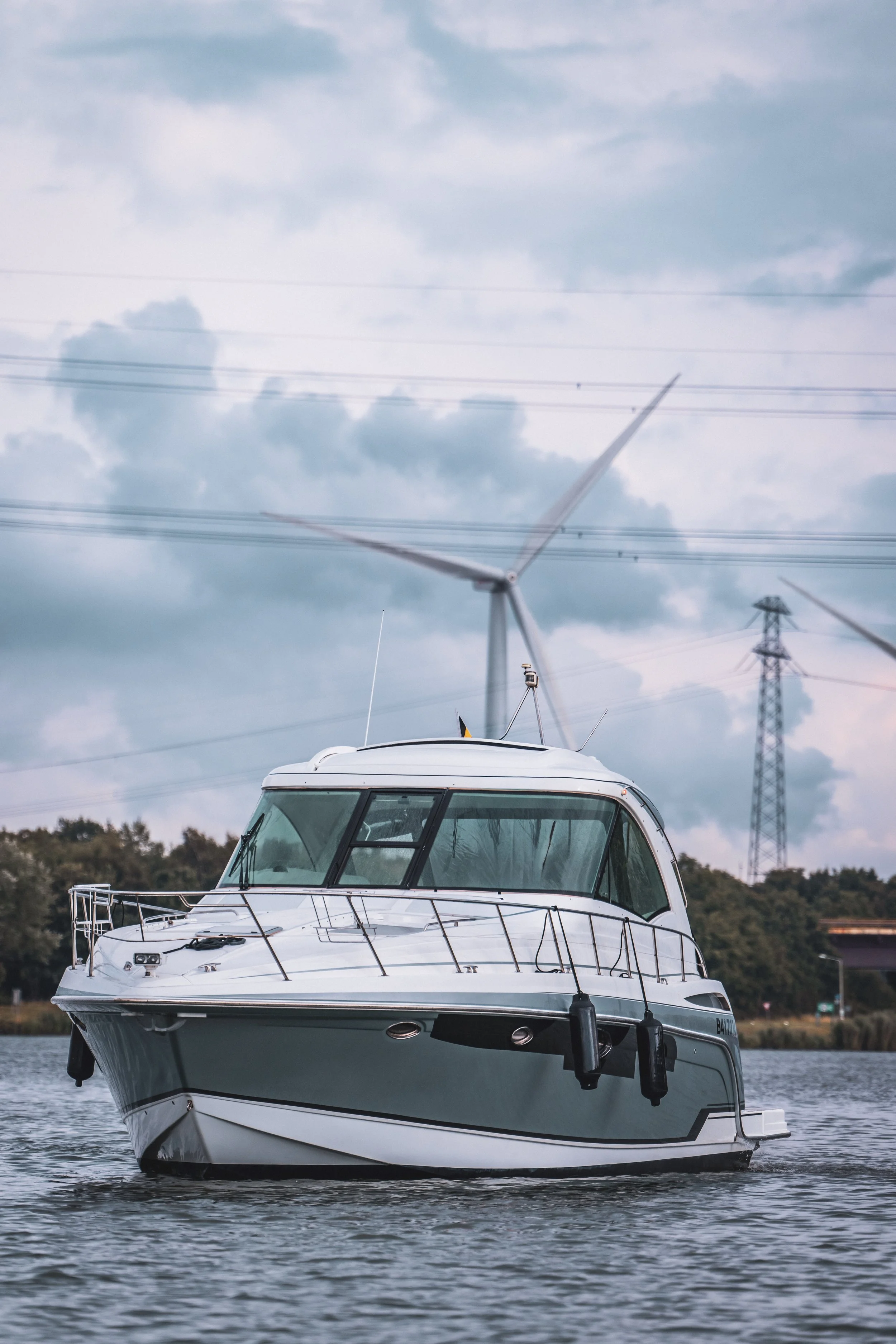 Professional photo of a modern motor yacht navigating through the water, captured on an overcast day.