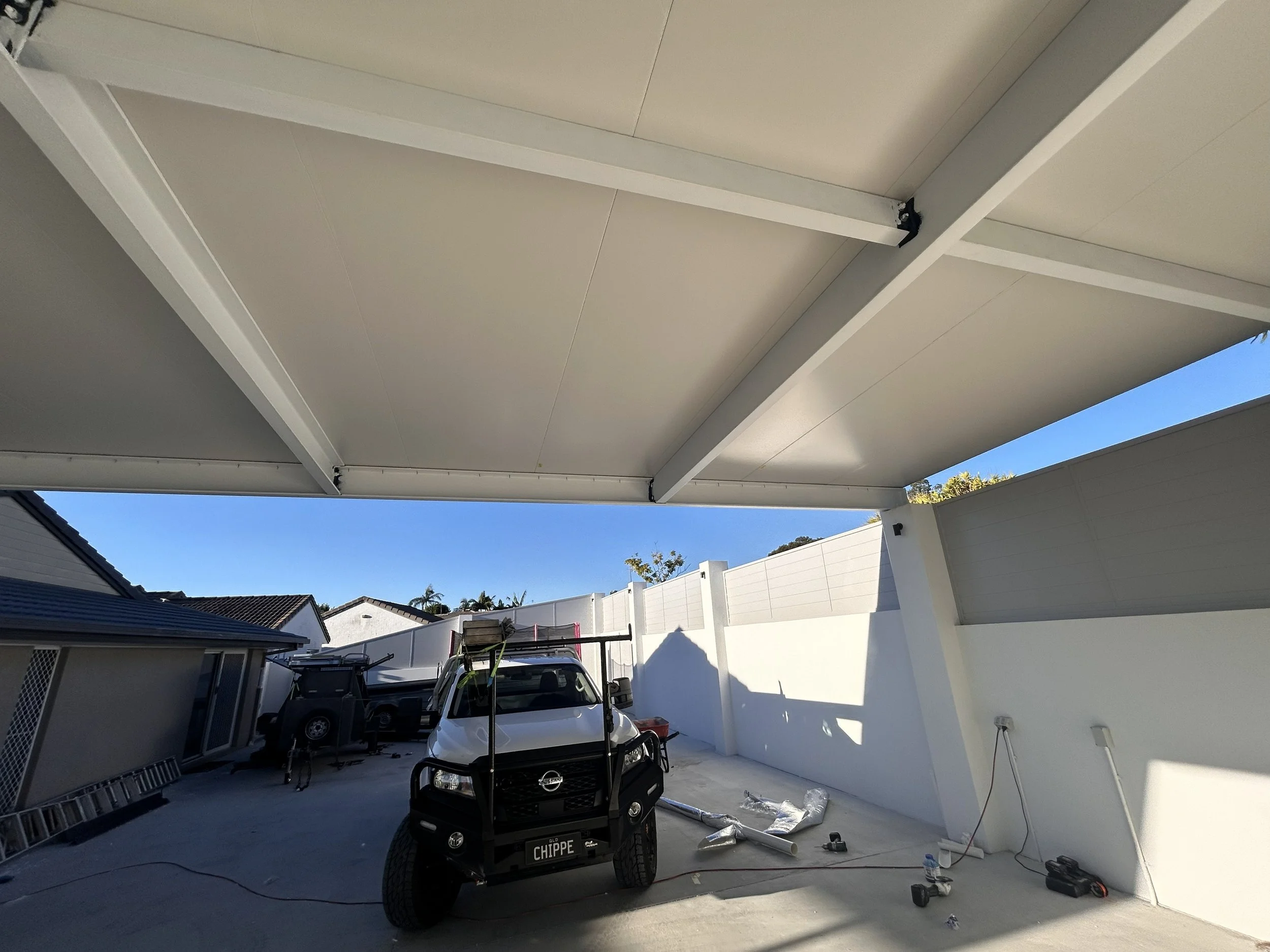 Underside of a white patio cover with construction tools and a small white utility vehicle underneath.
