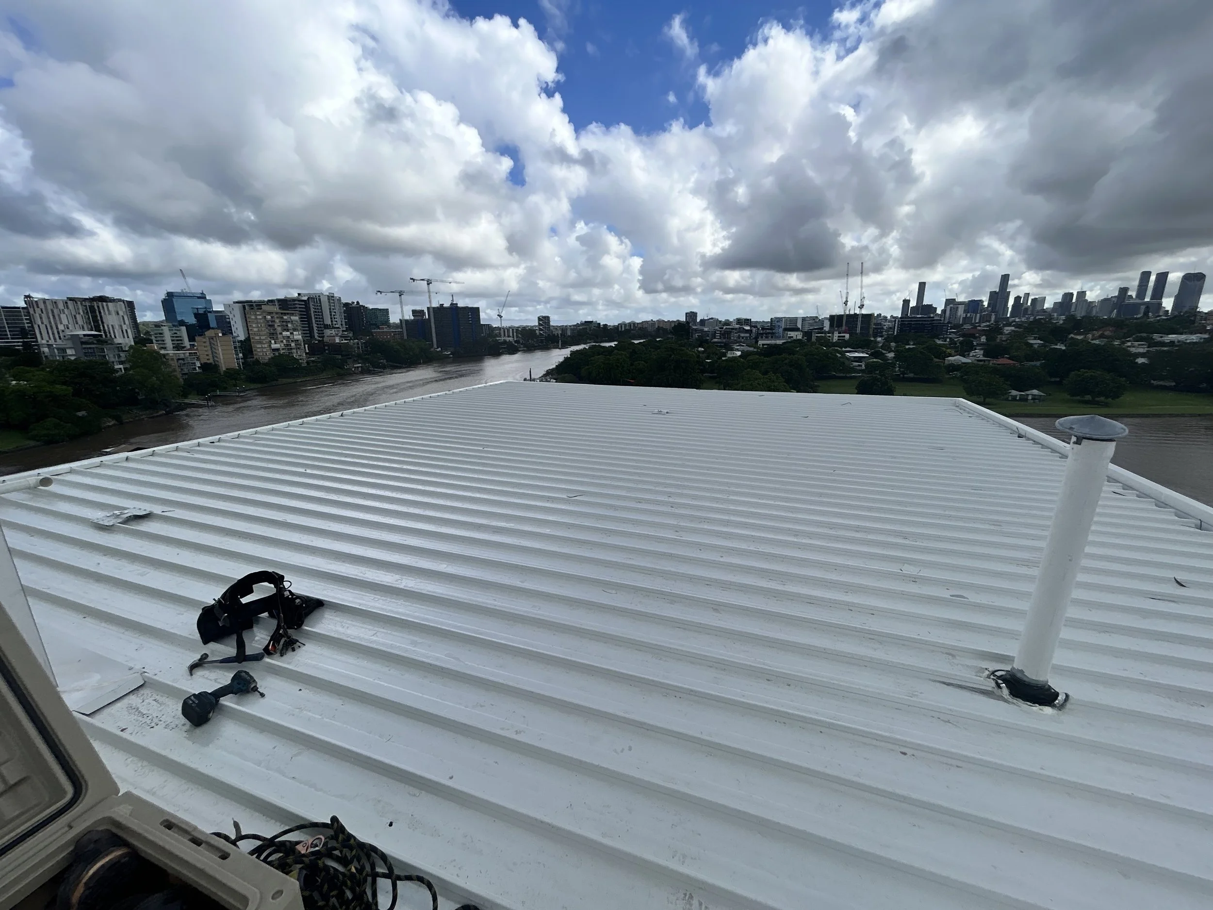 View from a rooftop showing a city skyline with tall buildings, a river, and a cloudy sky.