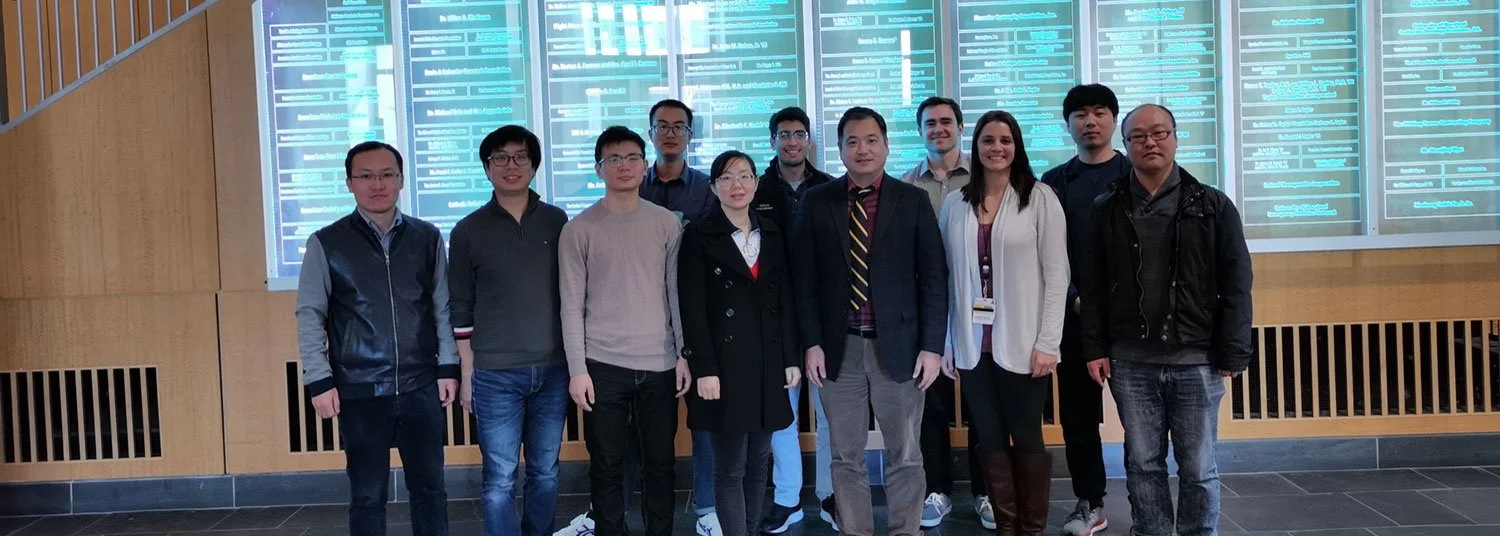 Group of eleven people standing in front of an electronic display wall with blue illuminated information panels.