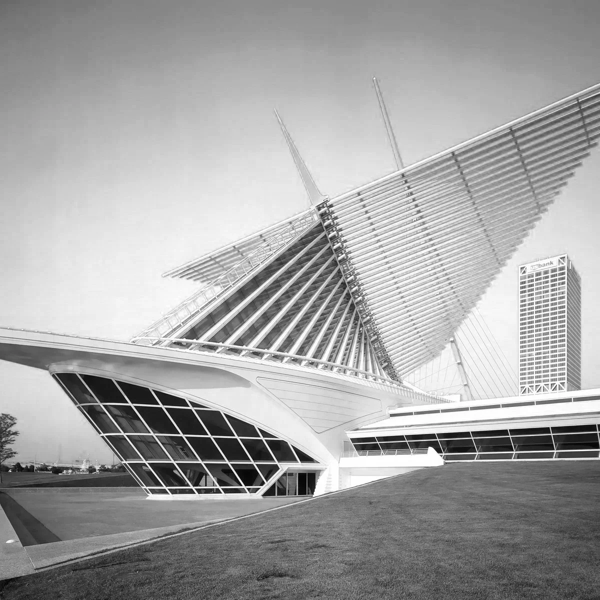 Black and white photo of the Milwaukee Art Museum, a modern architectural building with geometric and angular design, featuring a large slanted roof with radiating supports, glass windows.