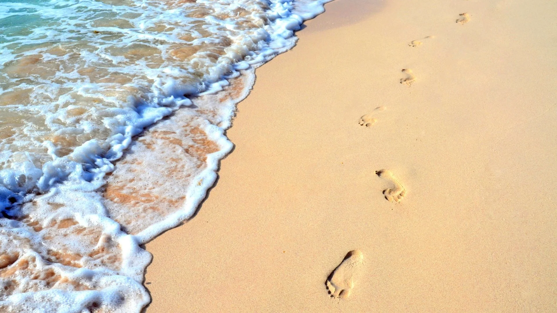 Footprints in the sand along the shoreline, a picture of a new beginning