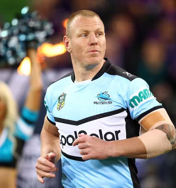A rugby player in a light blue and black jersey on the field during a game.