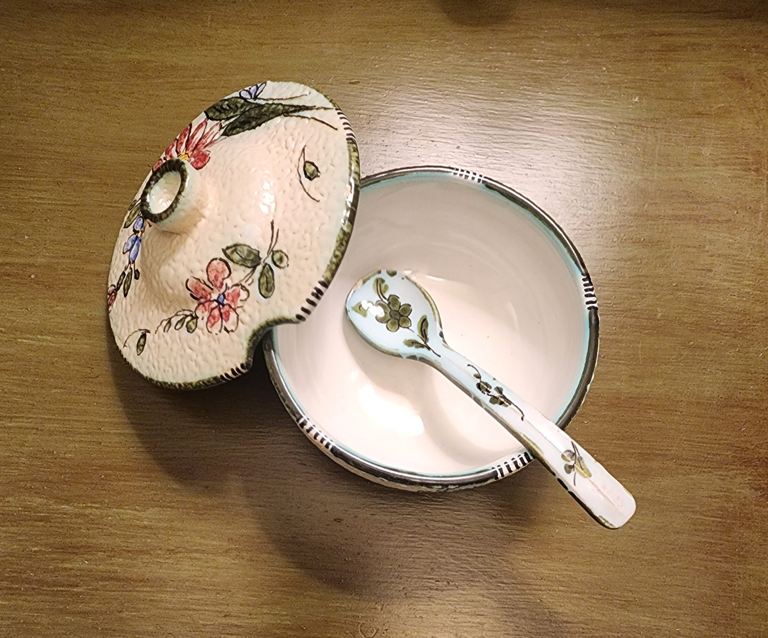 softly textured cream glaze vessel adorned with delicate floral motifs in warm reds, blues, and greens that’s romantic and inviting.