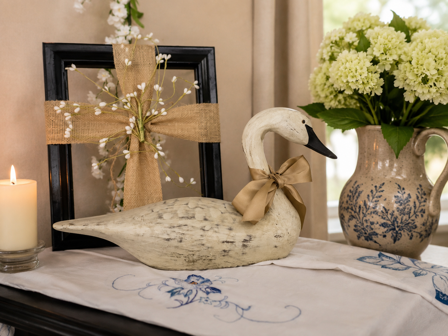 Destressed Resin Swan in front of a fabric cross styled around a frame.