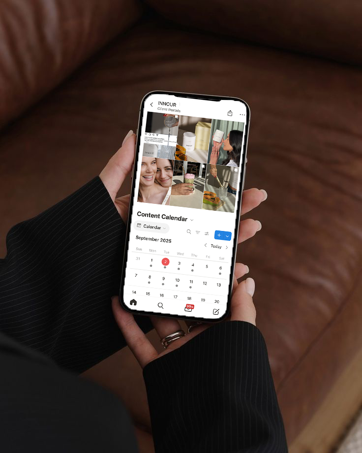 Person holding a smartphone displaying a content calendar for September 2025 with photos of drinks and people.