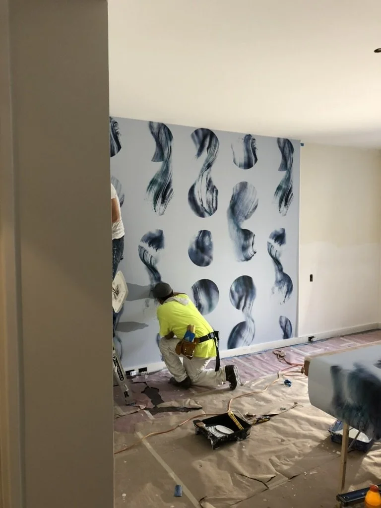 Installer applying custom patterned wallpaper, demonstrating detailed craftsmanship and alignment required for high-end interior finishes