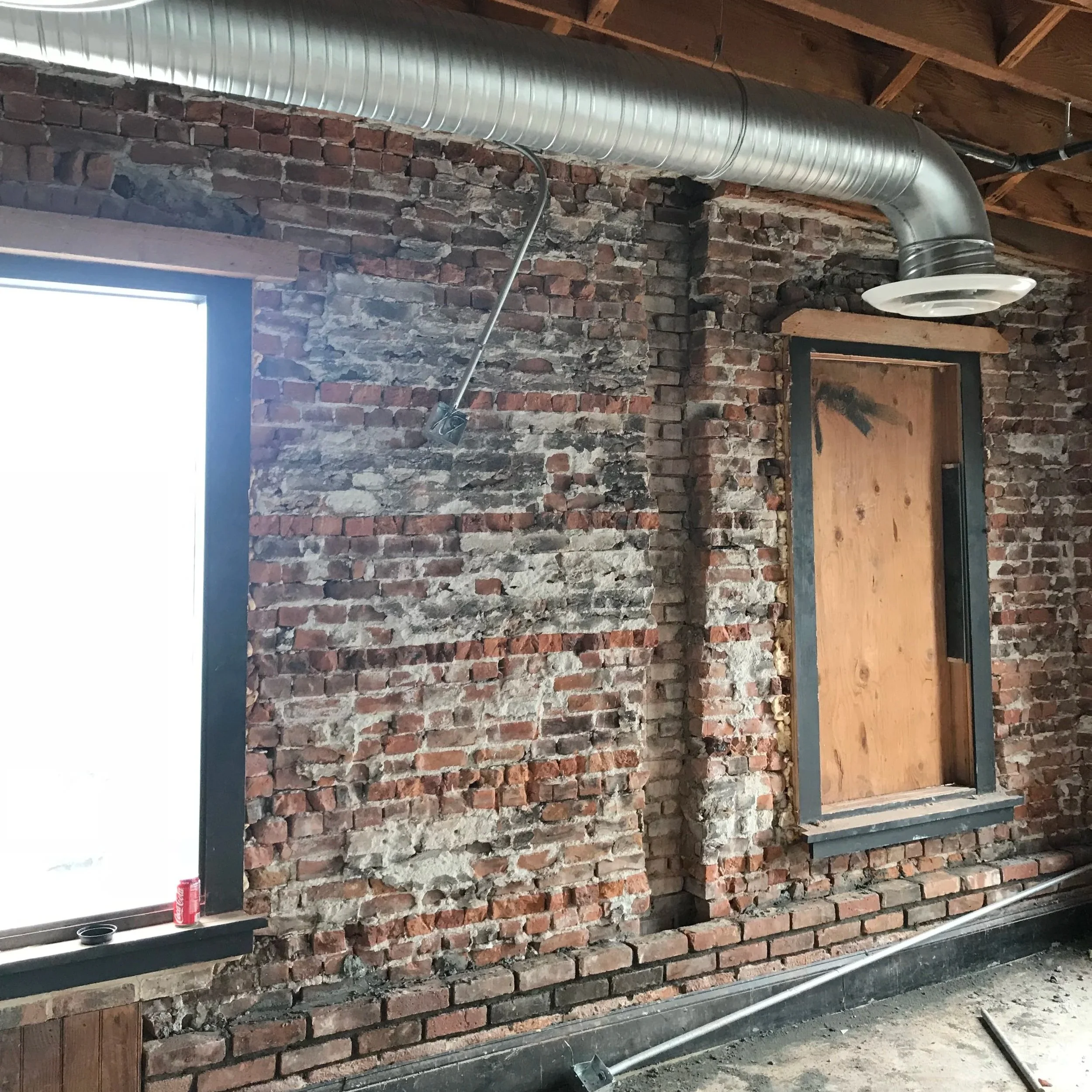 Structural renovation with exposed brick and ductwork in loft remodel demonstrating why hiring an interior designer increases renovation costs and project complexity