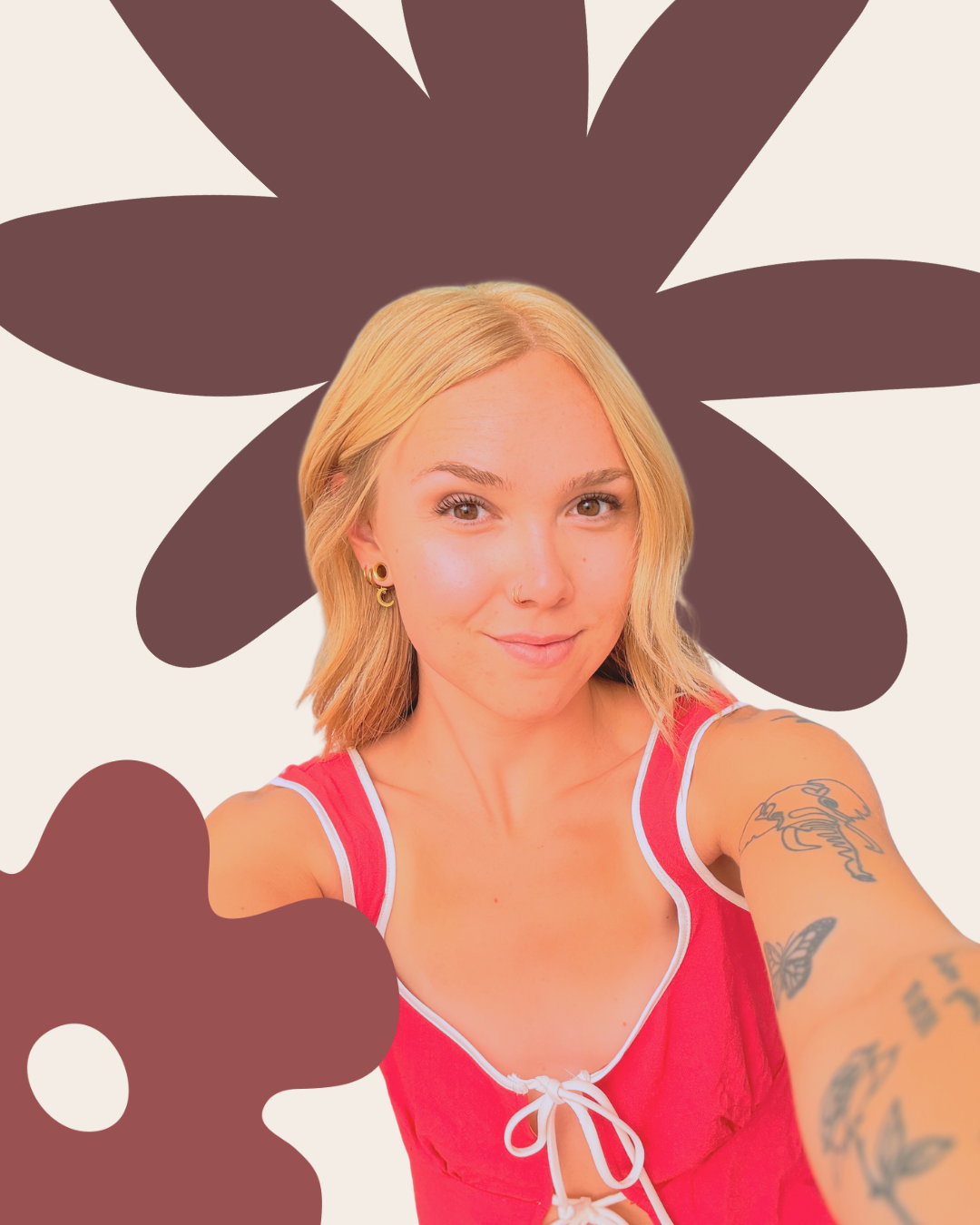 A young woman with blonde hair, wearing a red top with white trim, smiling and taking a selfie. She has tattoos on her right arm and is standing in front of a graphic background featuring a large, dark brown stylized flower or leaf shape.