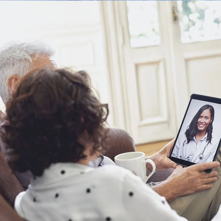 Older woman and man on a video call with a female doctor on a tablet.