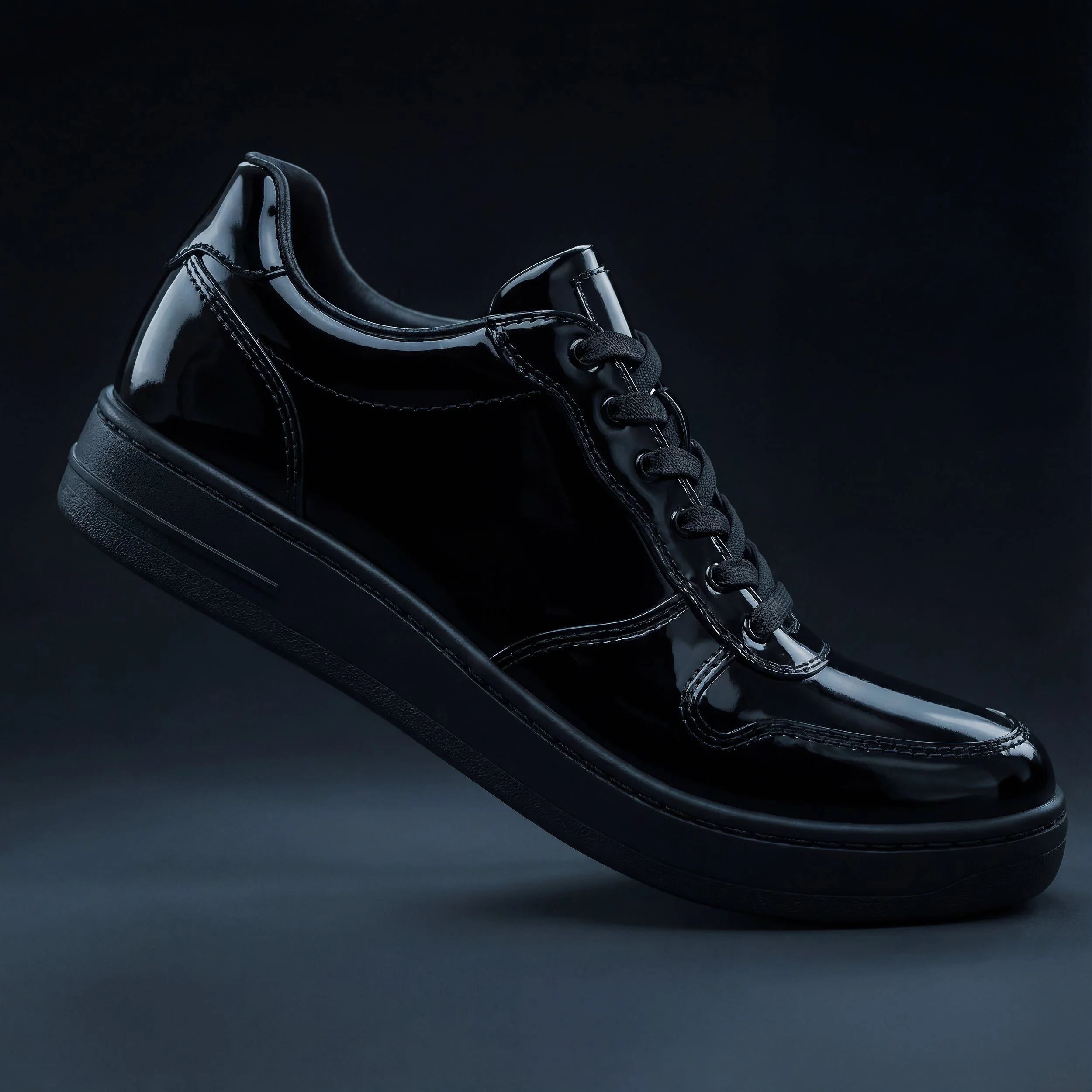 A close-up photograph of a black shiny leather sneaker against a dark background, showing the shoe's side, laces, and textured sole.