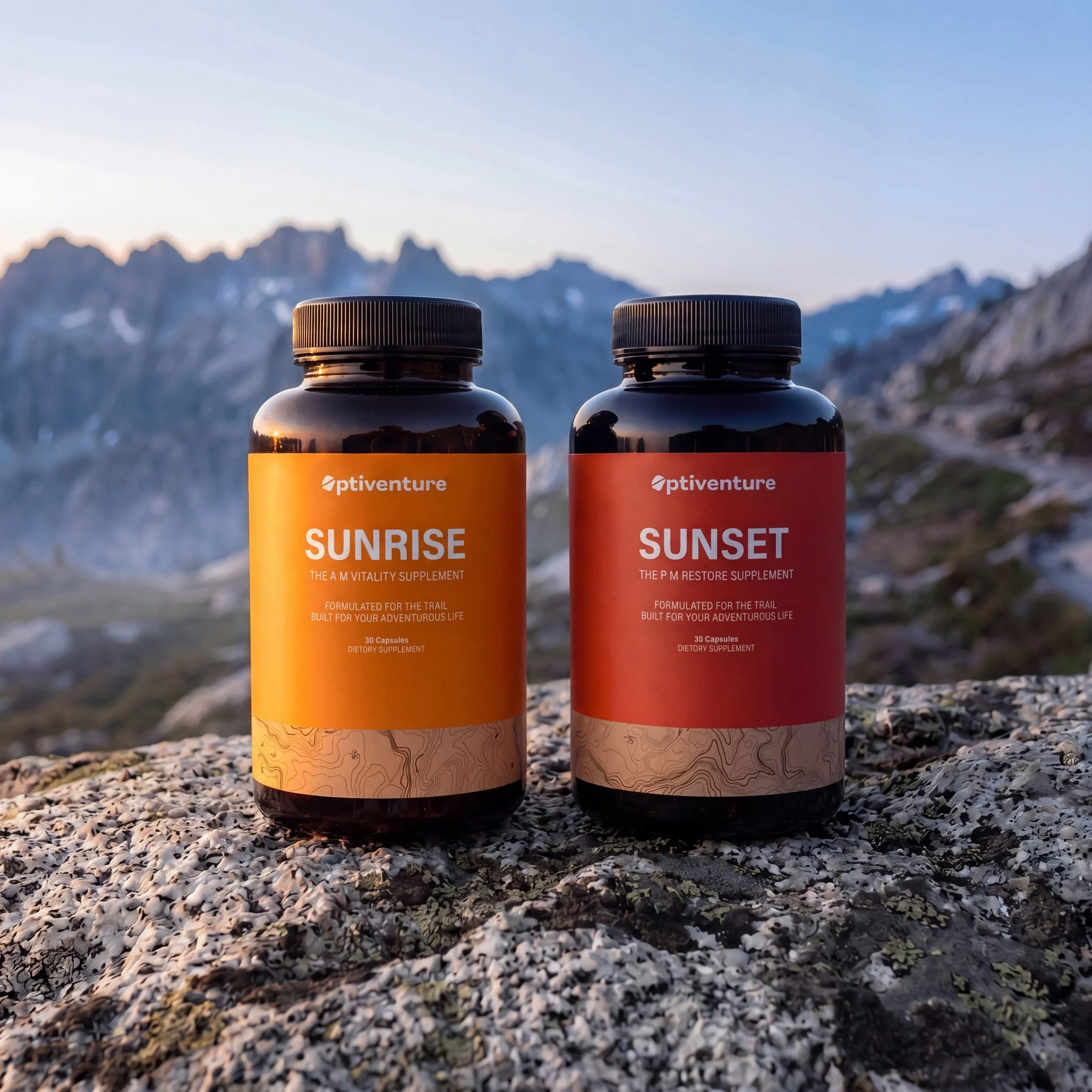 Two supplement bottles labeled 'Sunrise' and 'Sunset' placed on rocky ground with mountain peaks in the background during dusk or dawn.
